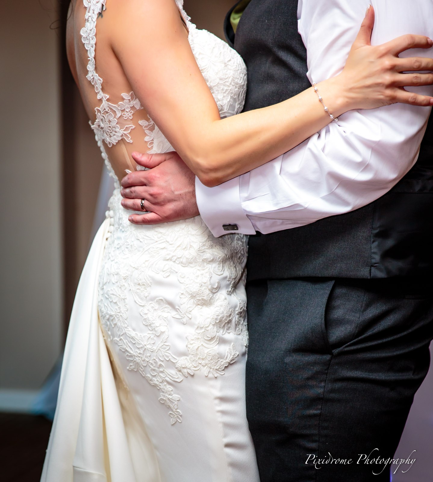 The couple in a close embrace, the open lace back of the gown on show