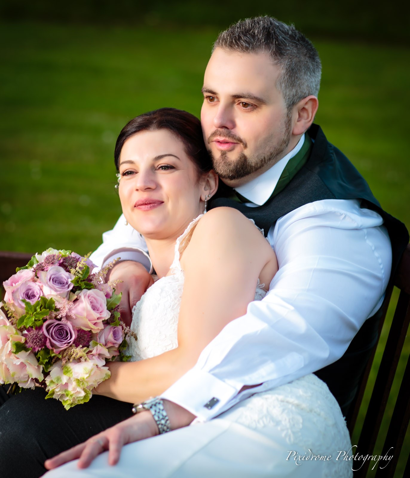 Bride and groom on a wooden bench in the grounds of Highfield Park