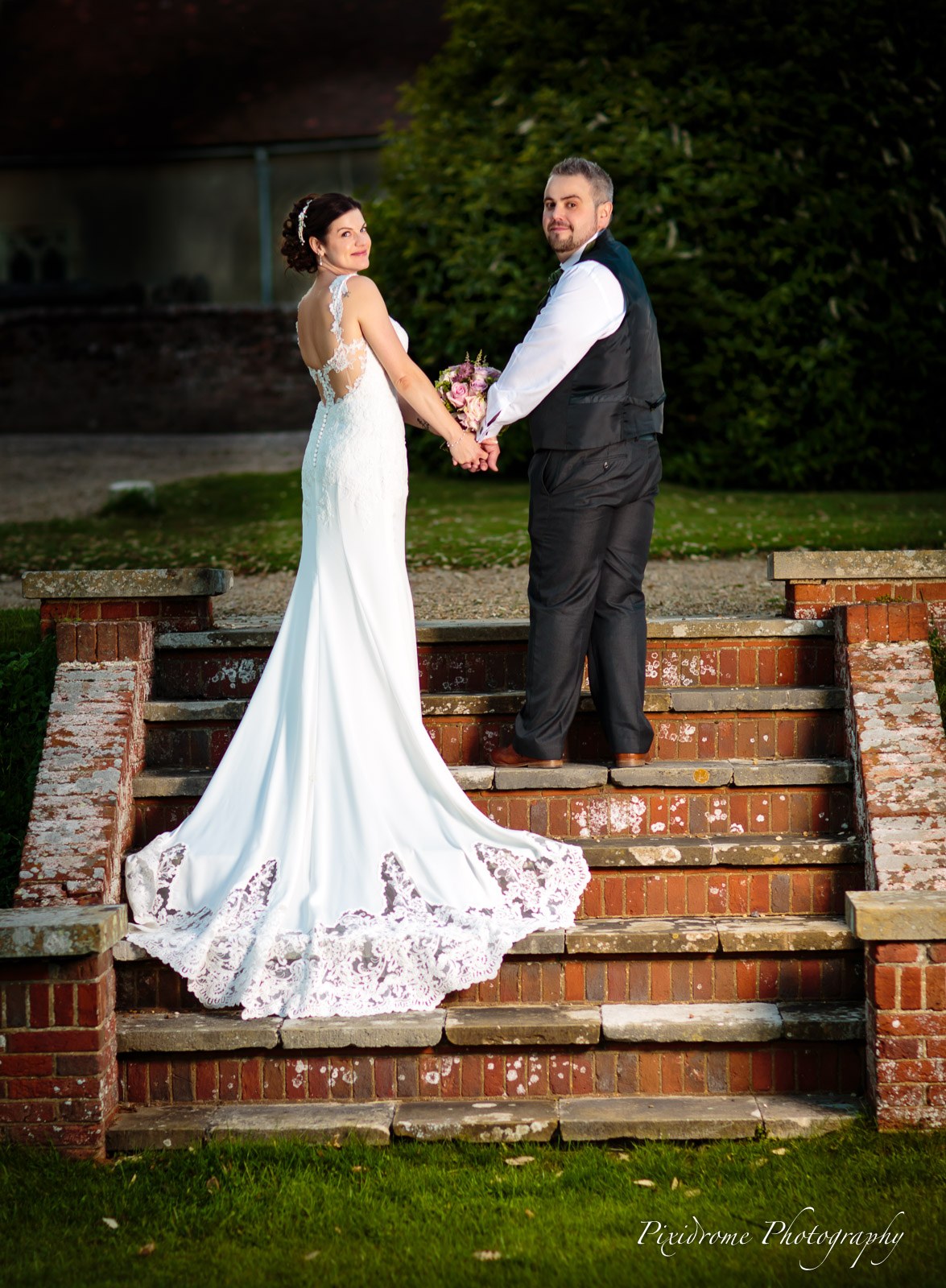 Bride and groom on weathered brick garden steps at Highfield Park