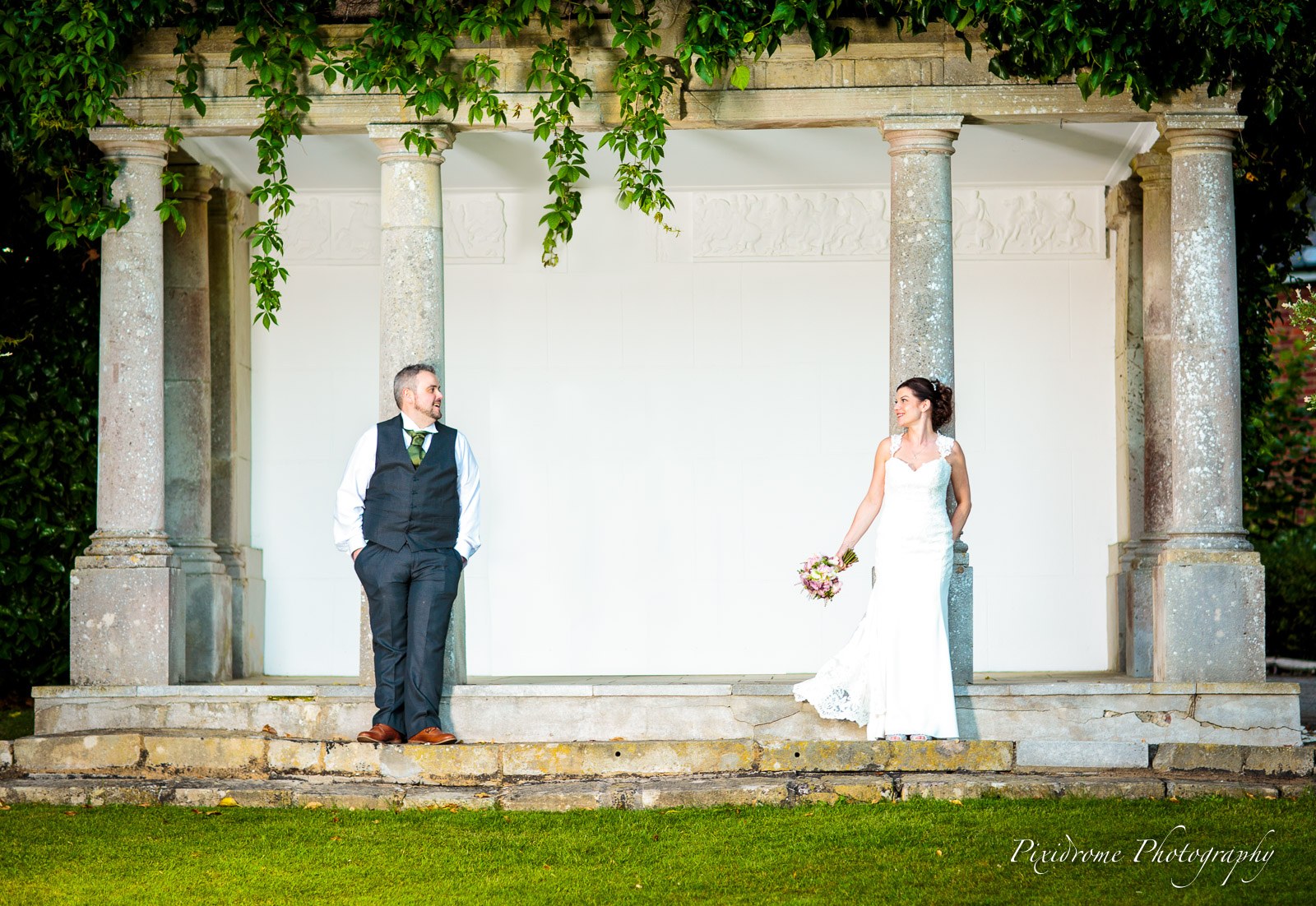 The couple framed by the ivy-draped stone colonnade in the grounds of Highfield Park
