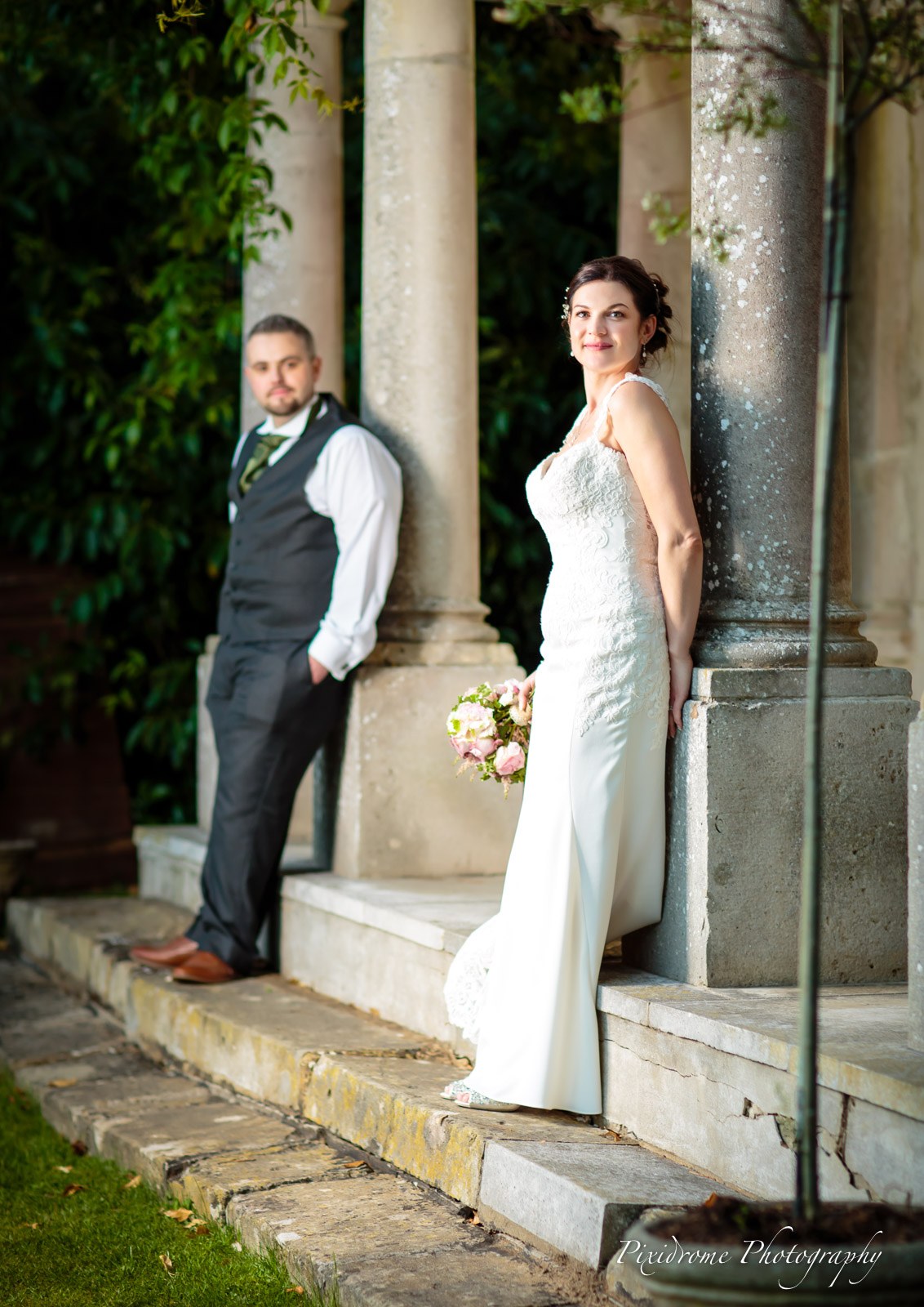 Bride and groom posed on the steps of the stone garden colonnade