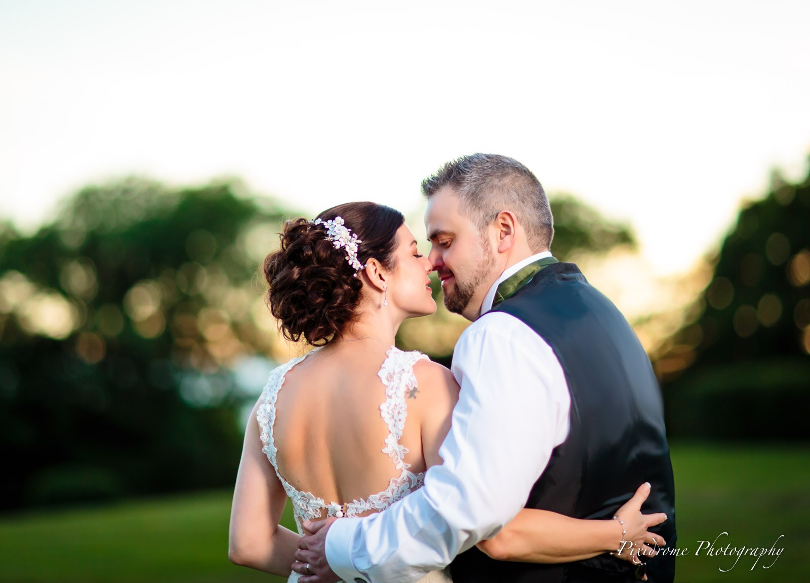 Bride and groom kissing on the lawn in the golden evening light