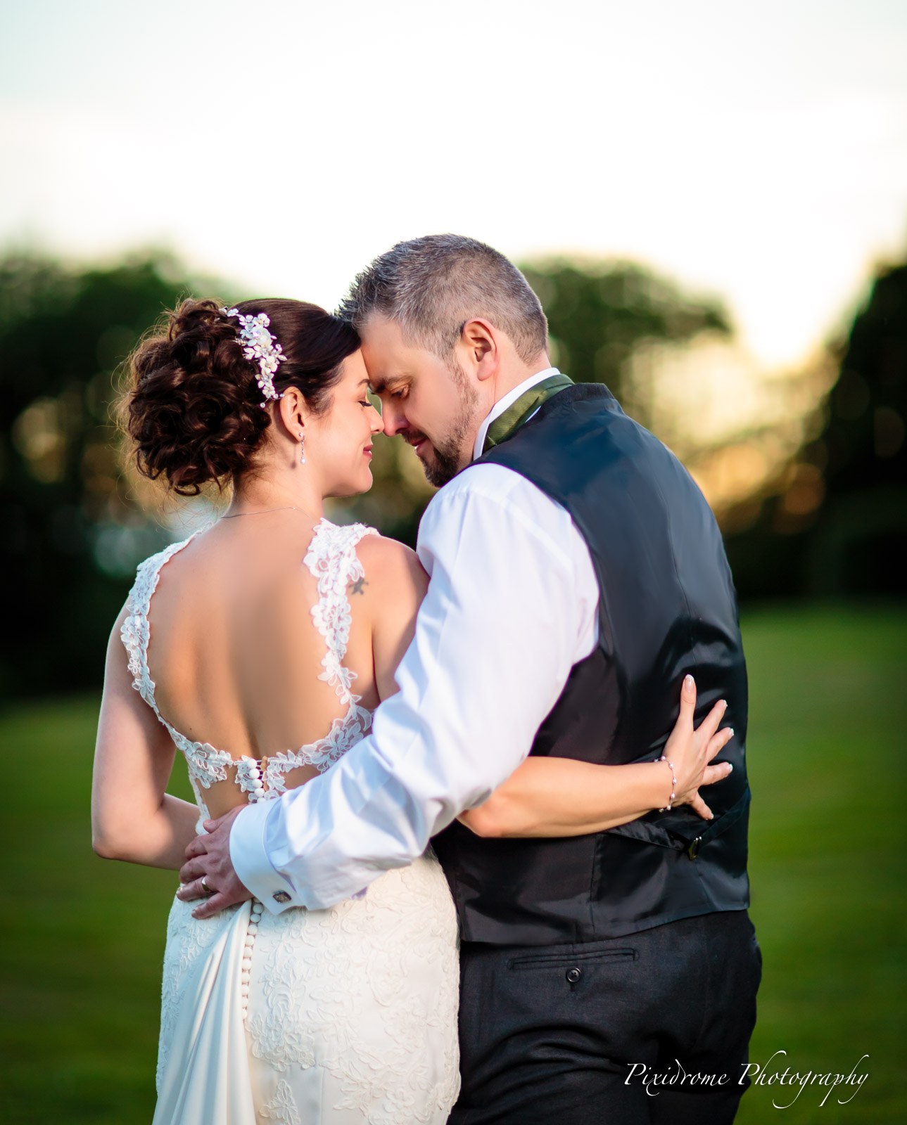 The couple forehead to forehead in the parkland at dusk