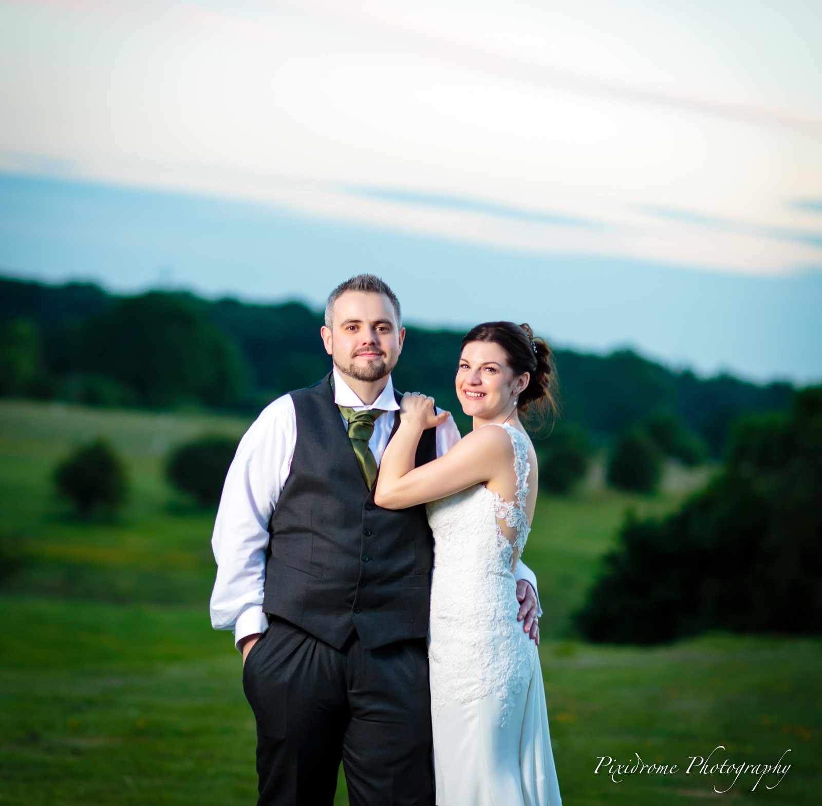 Bride and groom together in the wide meadow at twilight