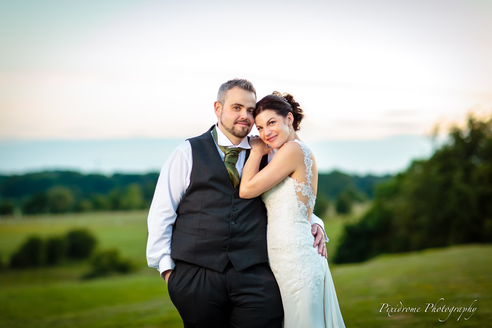 The couple leaning together in the dusky evening meadow