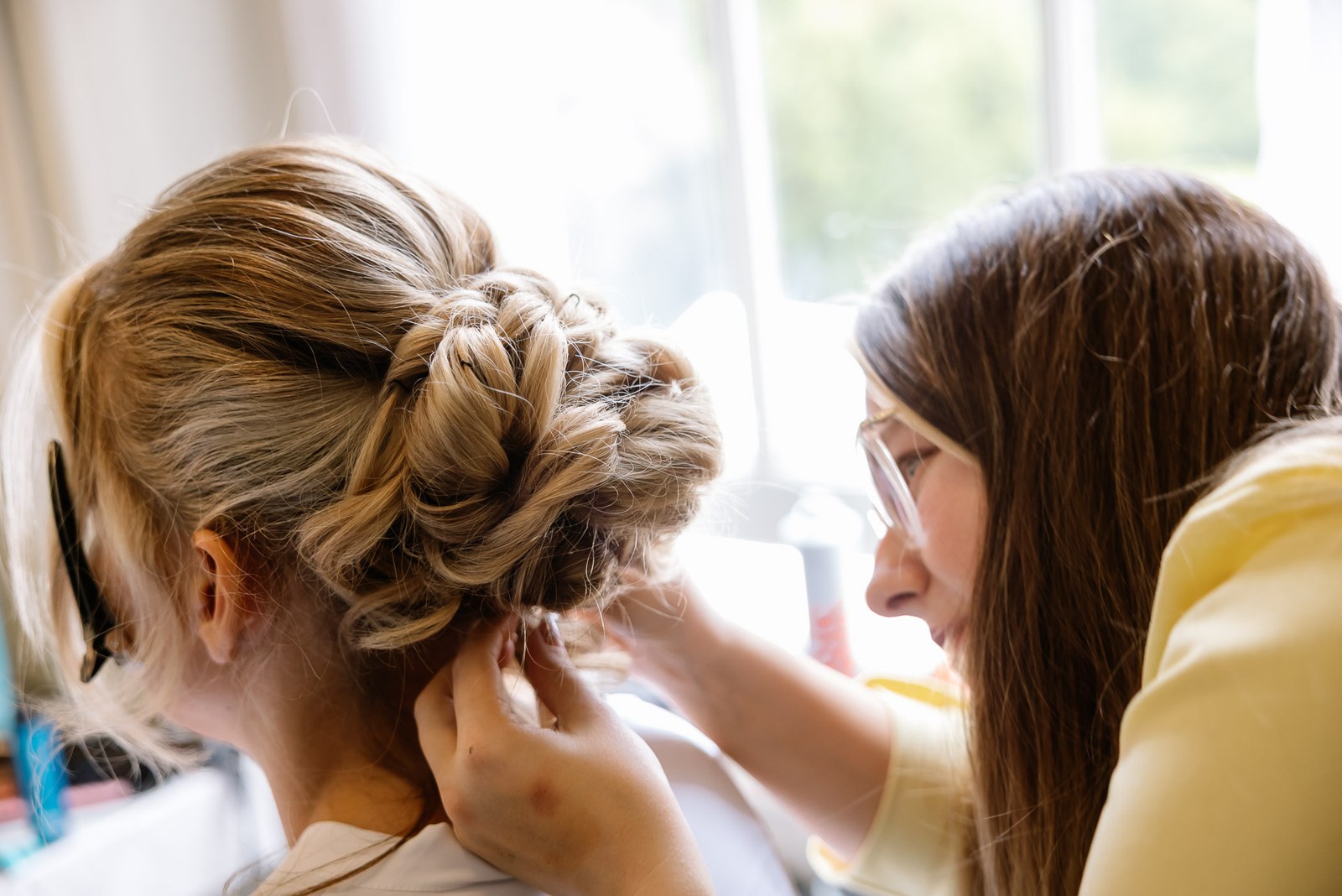 A stylist pinning the bride's hair into an elegant updo