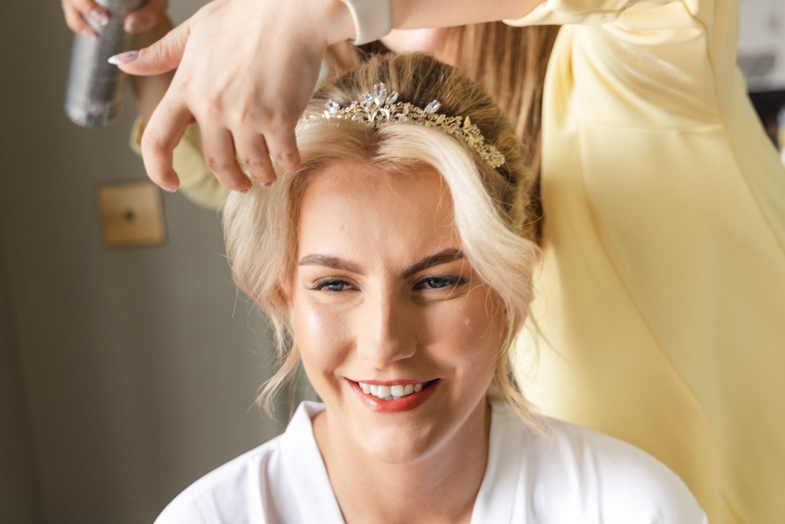 Bride smiling as her tiara and hair are set with spray