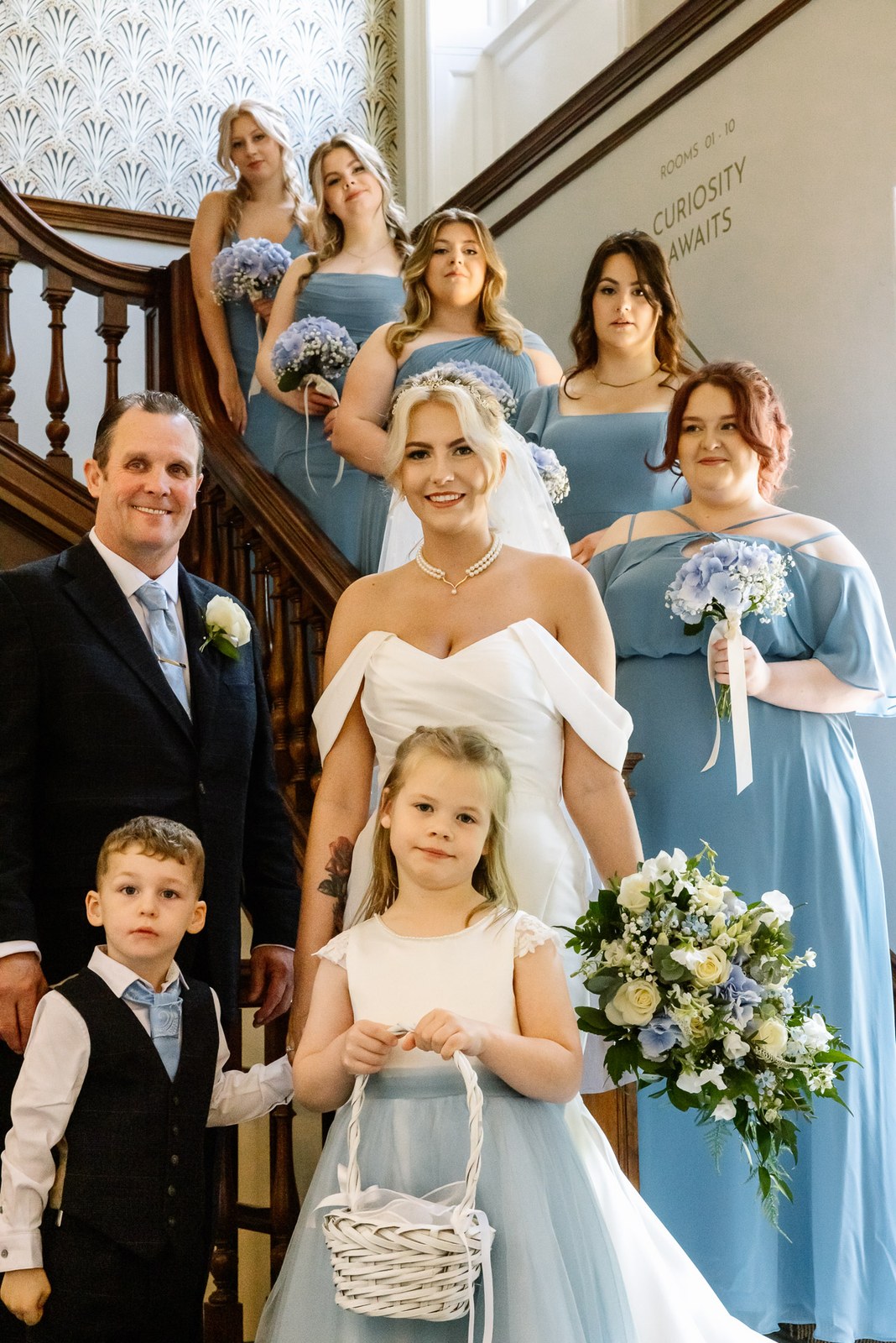 The bride with her father, bridesmaids and children on the grand staircase at Hunton Park Hotel
