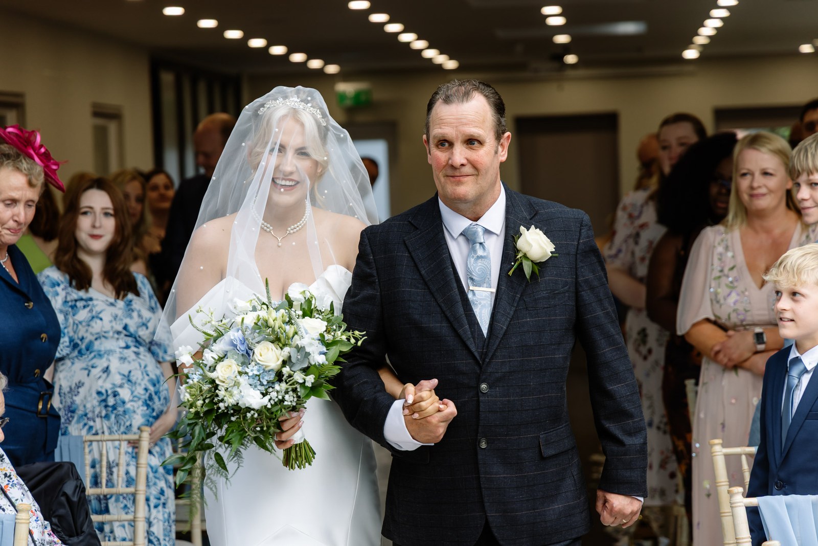 Bride and father entering the aisle between the standing guests