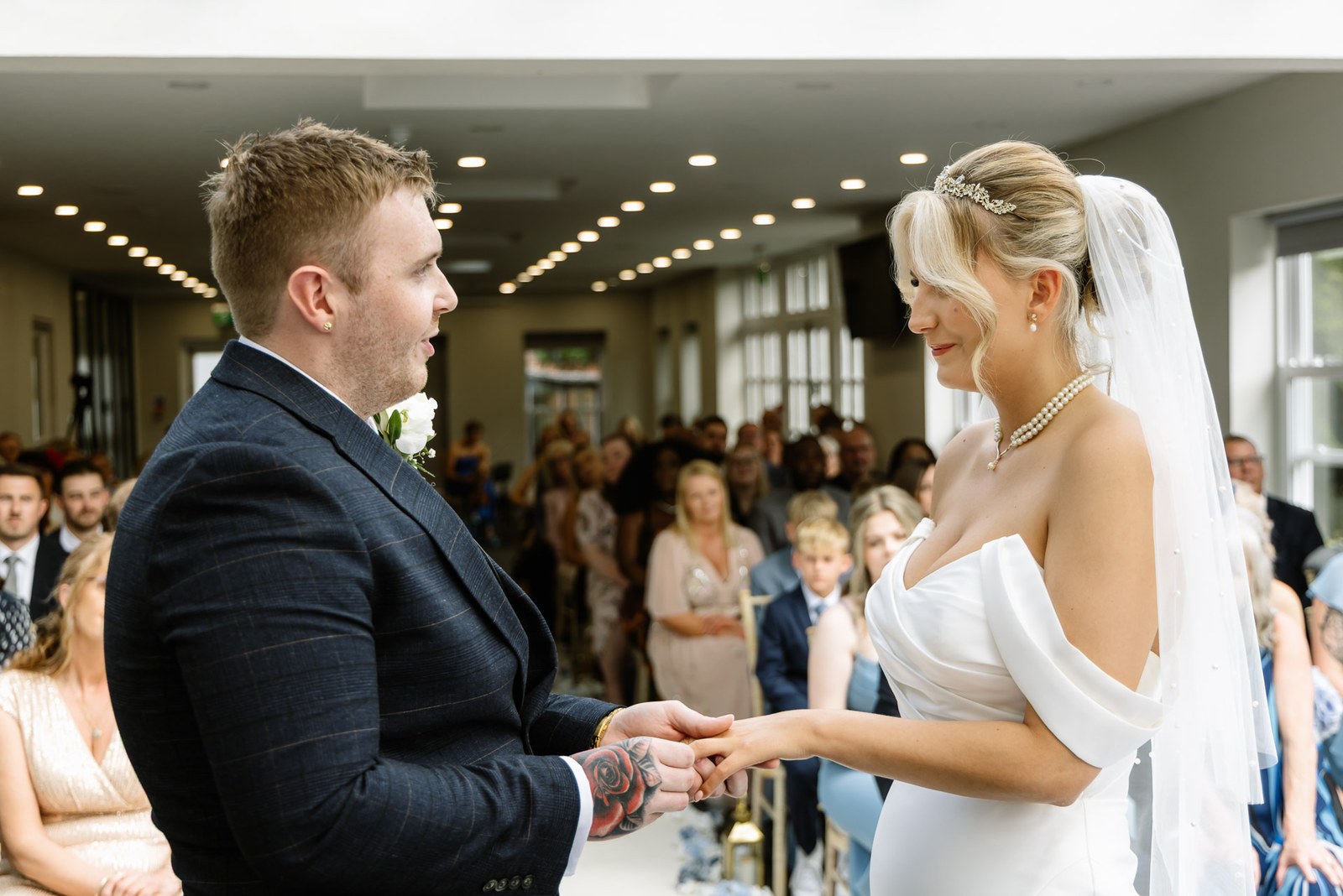 The couple holding hands during the ceremony with guests seated behind