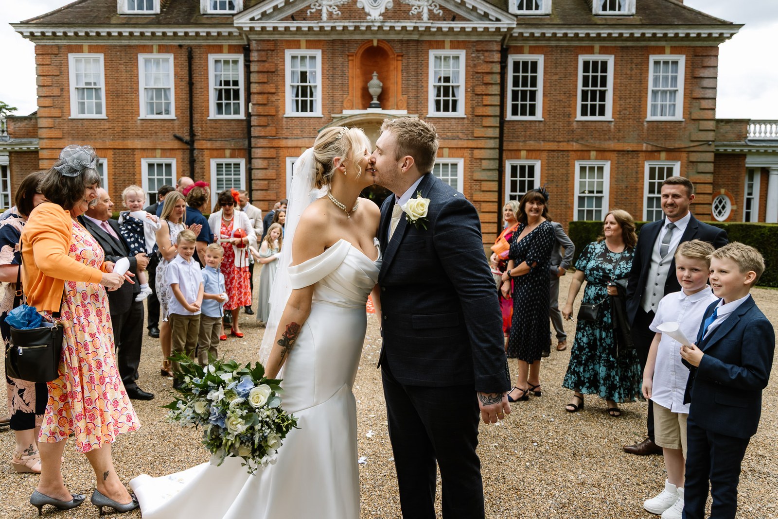 Bride and groom kissing before the red-brick Georgian frontage of Hunton Park Hotel