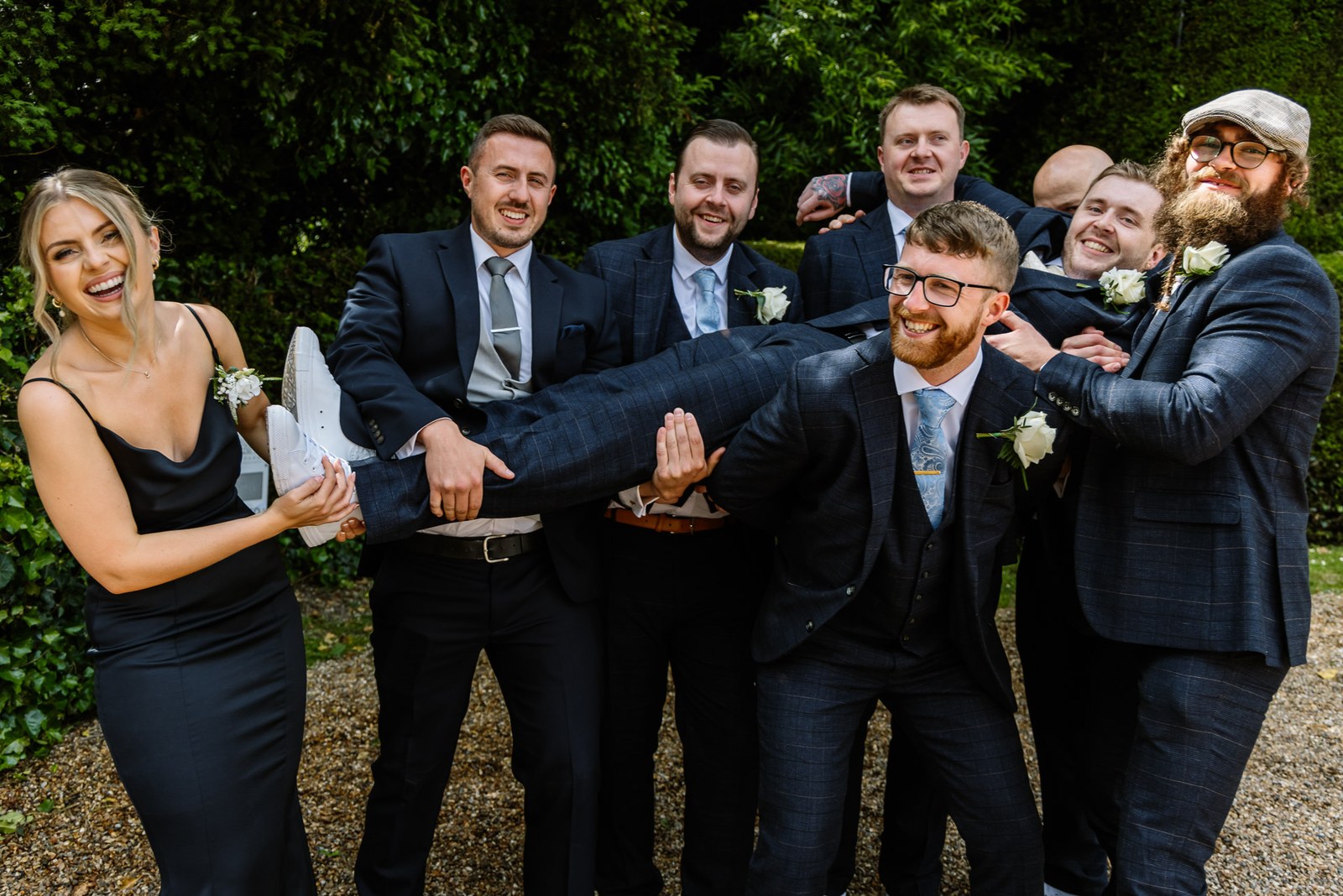The groomsmen hoisting one of their own off his feet, everyone laughing