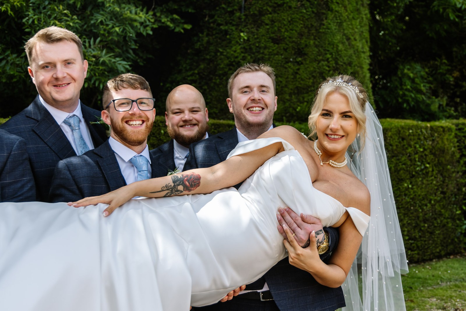 The groomsmen carrying the bride horizontally as she grins