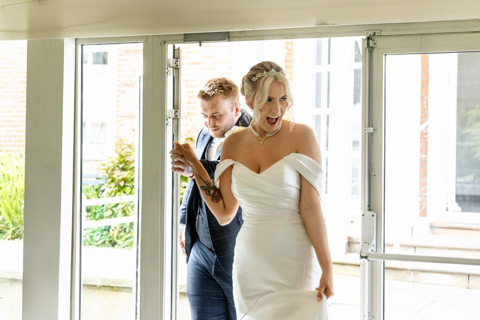The bride laughing as the couple step in through the garden doors