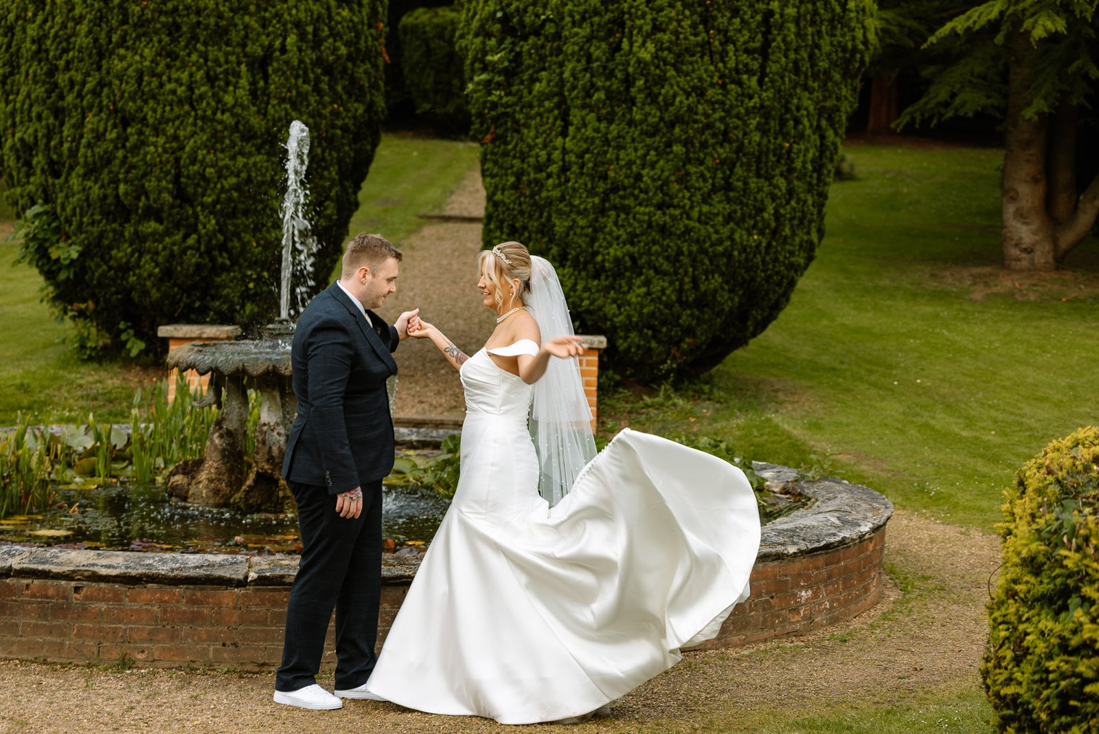 The groom spinning the bride, her skirt swinging out beside the ornamental fountain