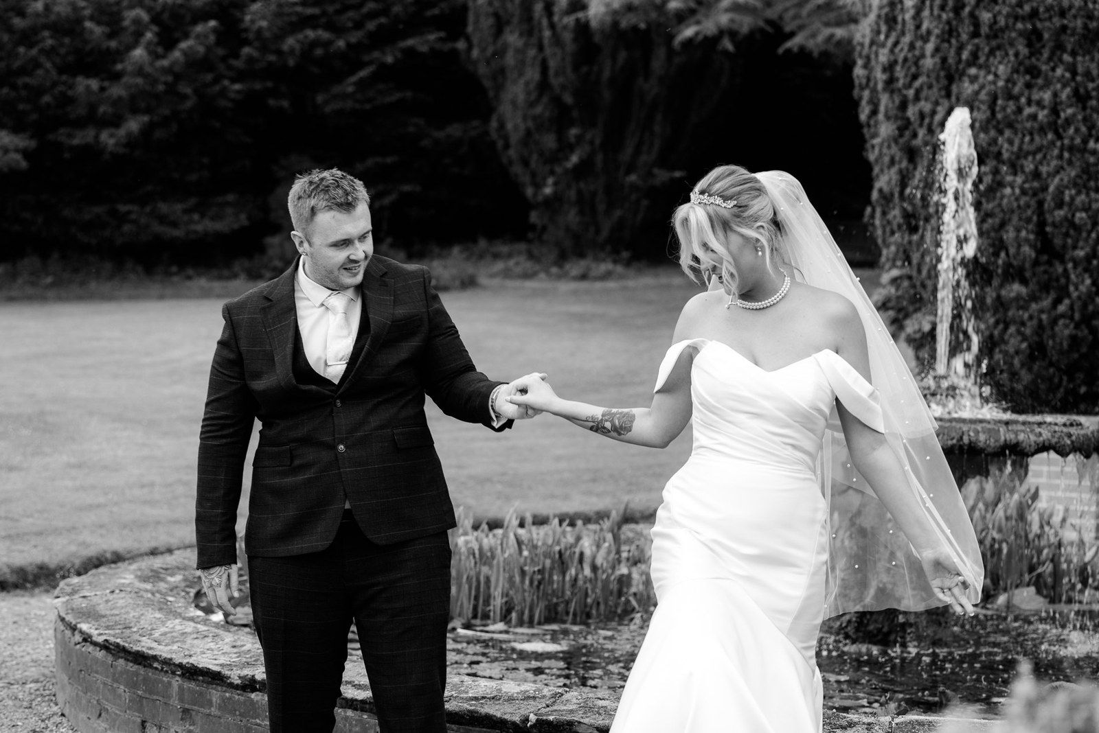 Black-and-white moment of the couple by the fountain in the gardens