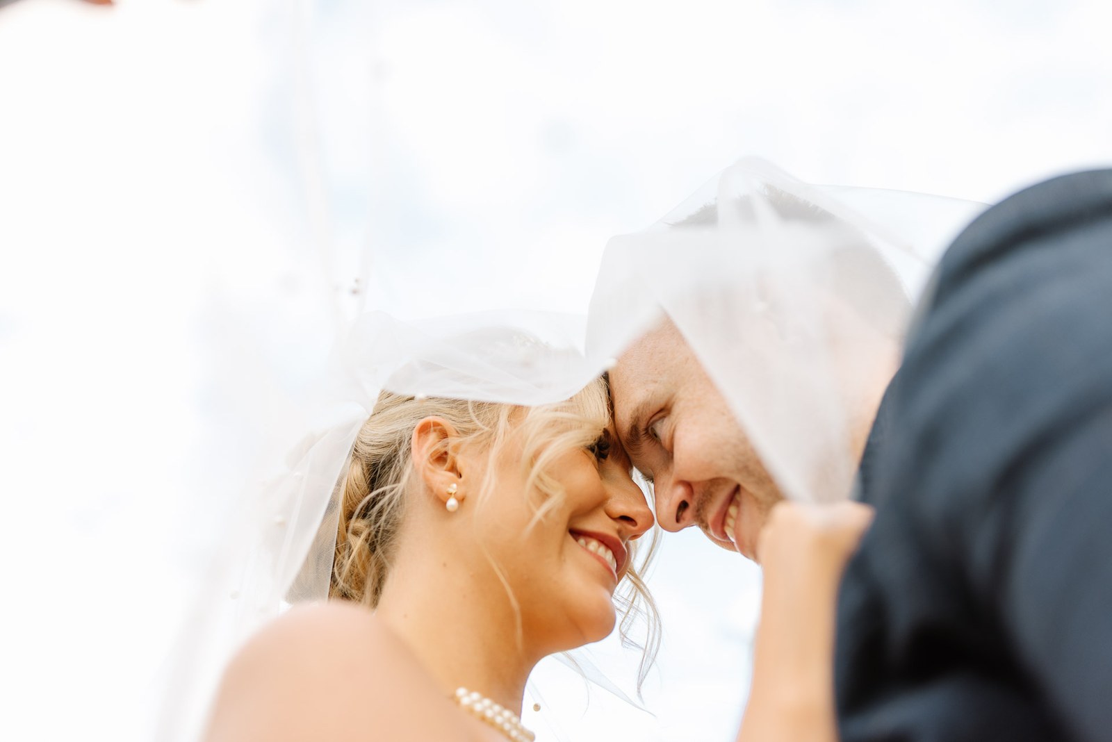 Bride and groom forehead to forehead beneath her veil