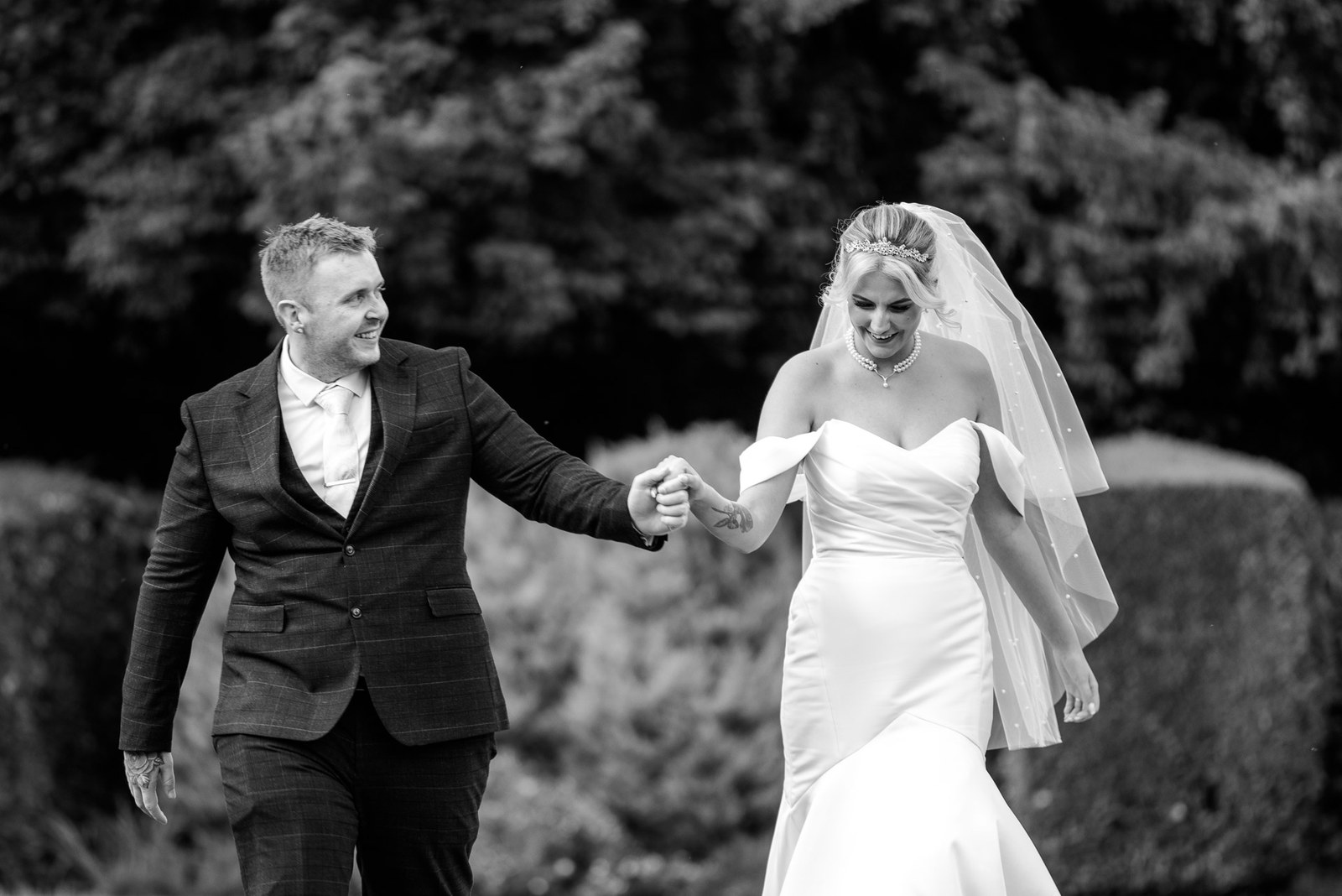 Black-and-white shot of the couple walking hand in hand through the grounds