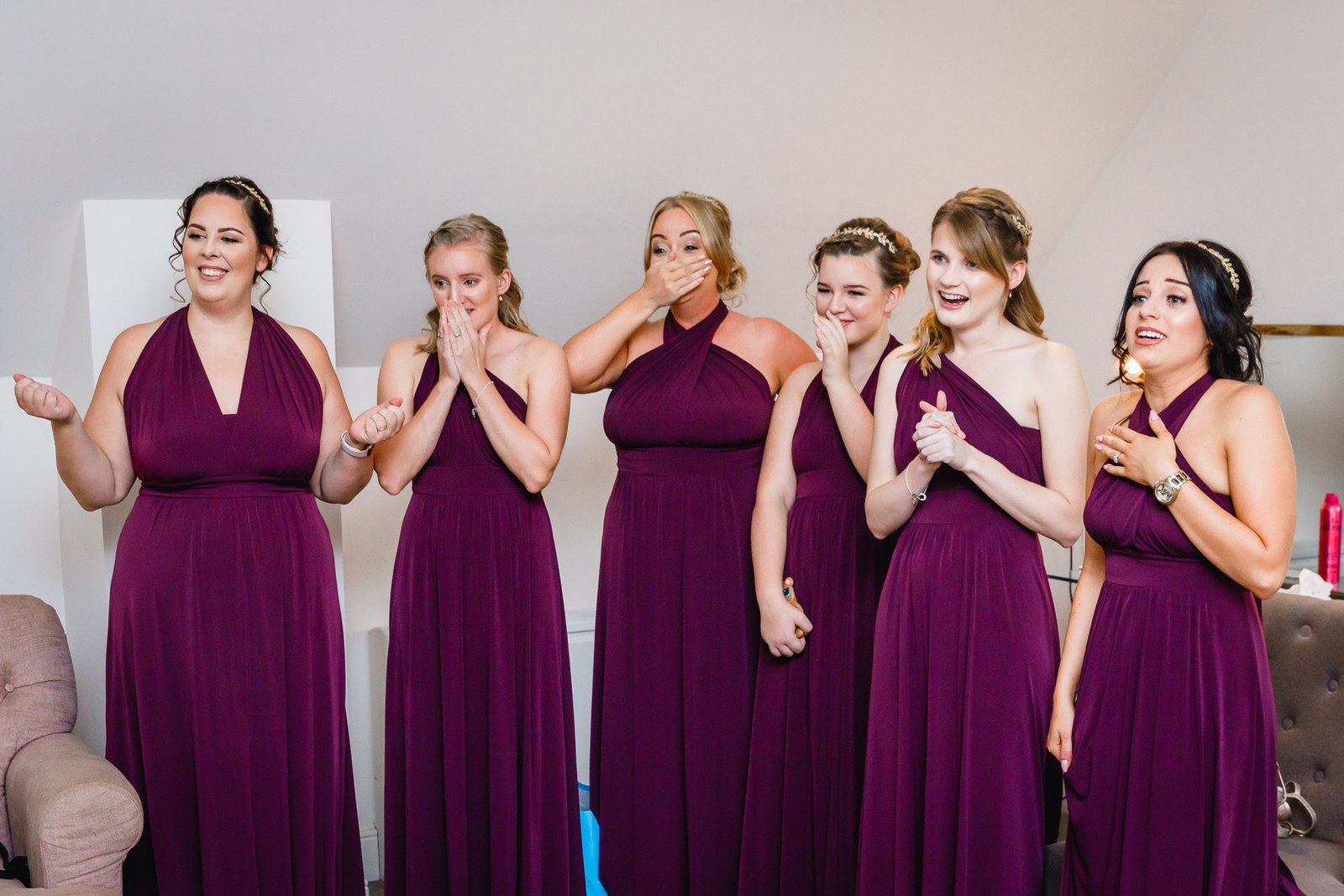 Bridesmaids in aubergine gowns overcome as they see the bride ready