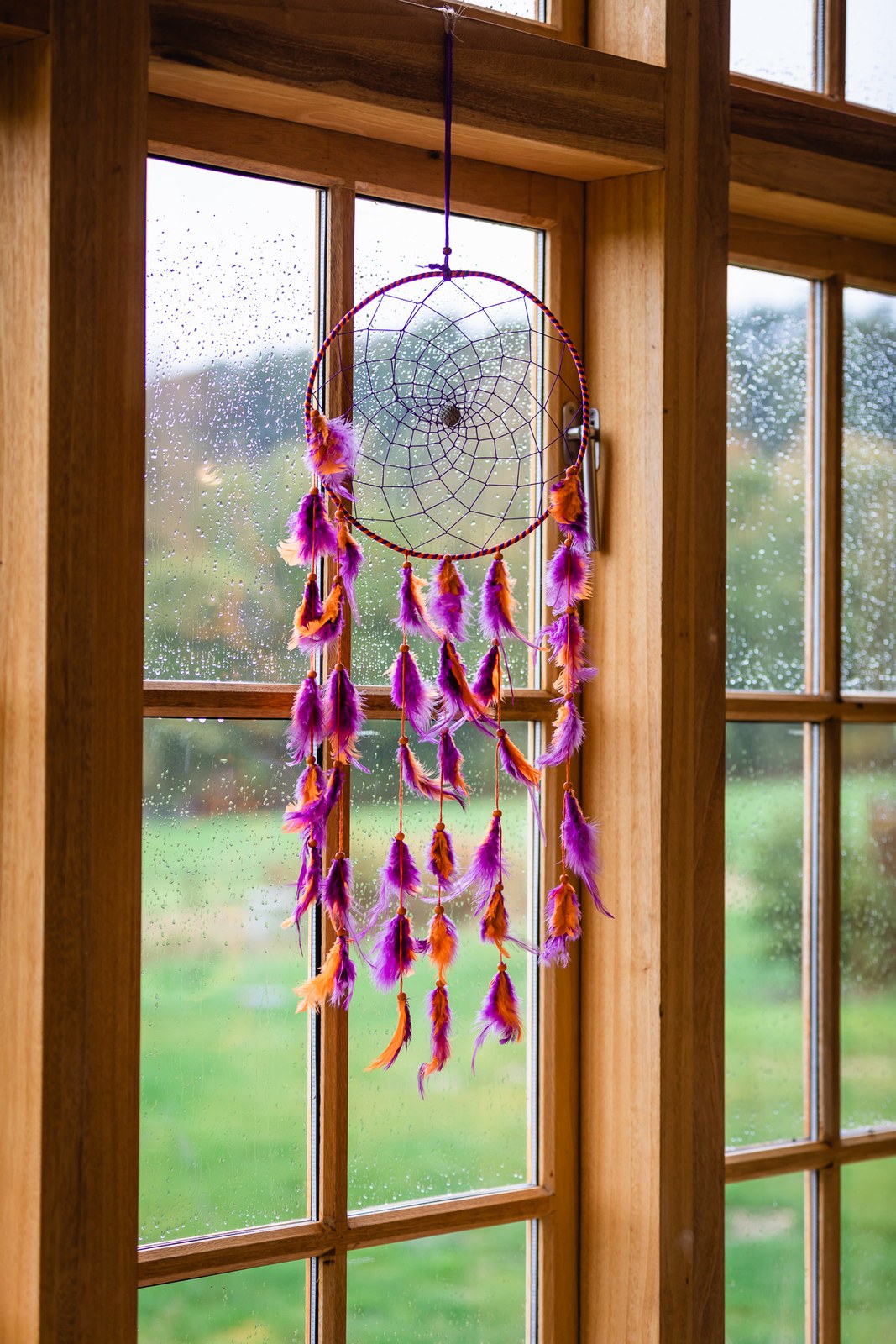 A feathered dreamcatcher hanging in the oak-framed window over the countryside at Hyde House