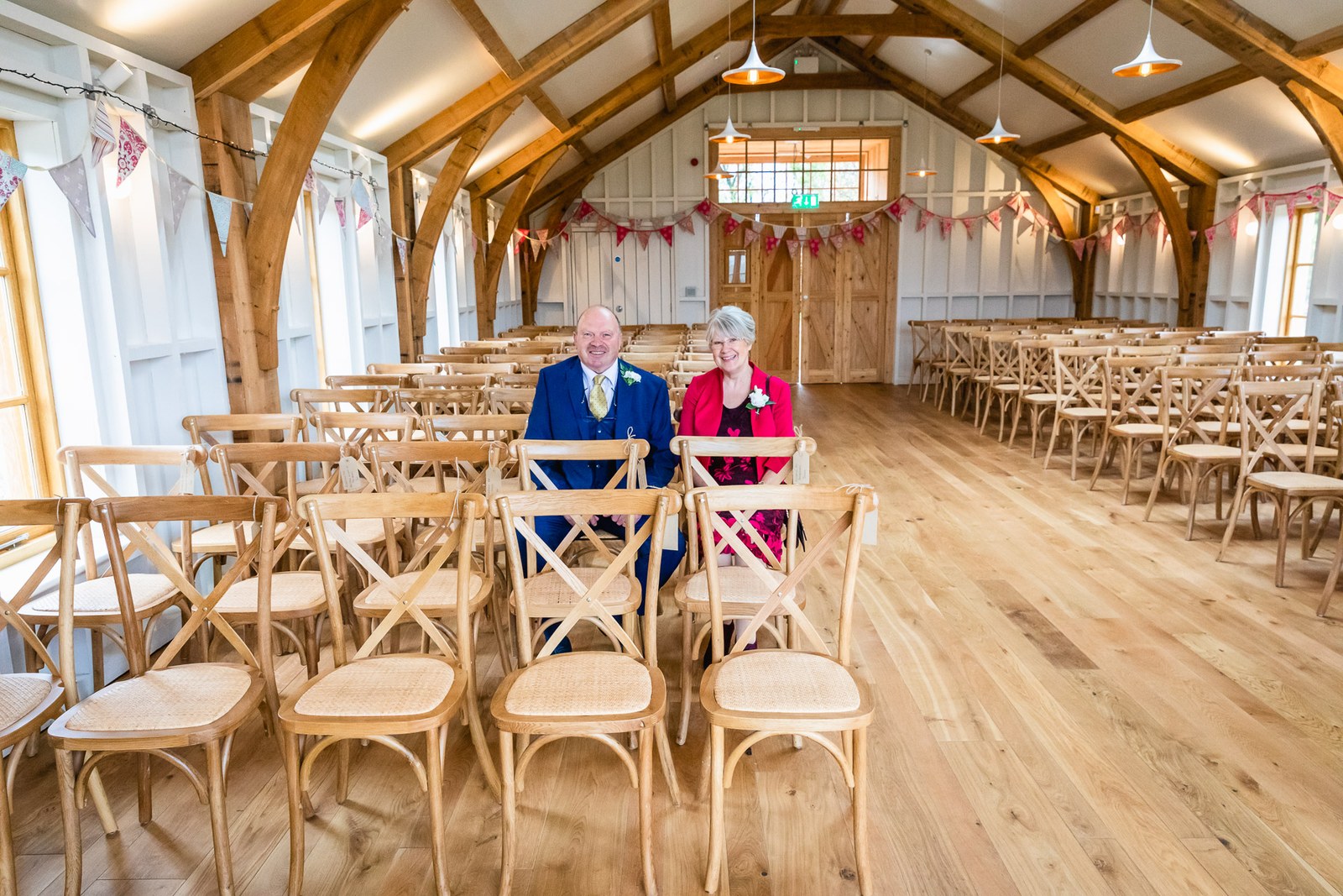 The oak-framed ceremony barn at Hyde House dressed with bunting and cross-back chairs
