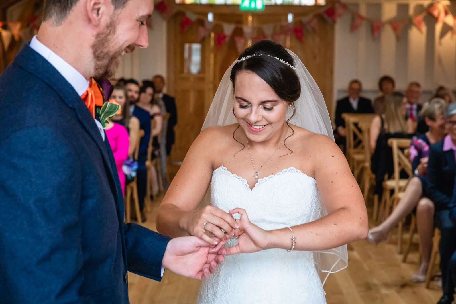 The couple holding hands as the bride places the ring on the groom's finger