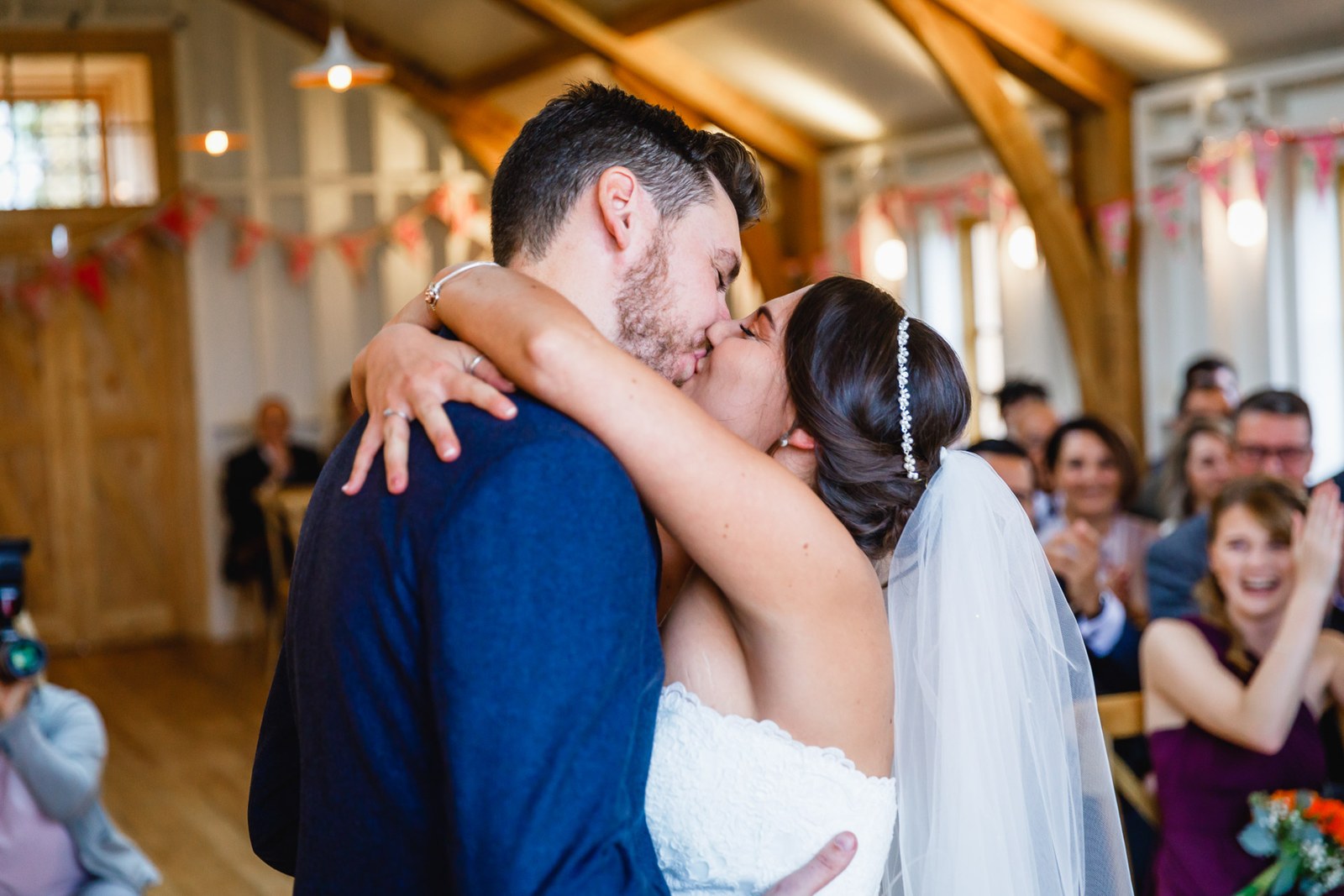 The couple's first kiss as married as guests applaud in the barn