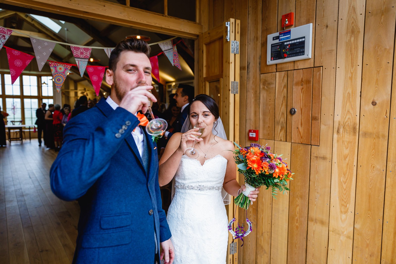 The newlyweds sharing a celebratory drink beside the timbered barn wall