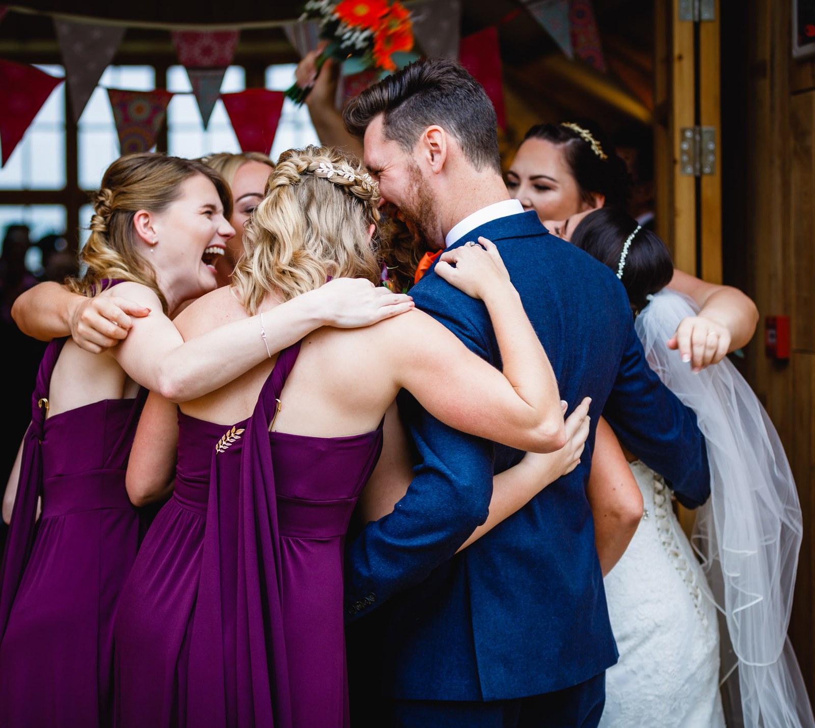 A joyful group hug between the couple and their bridesmaids