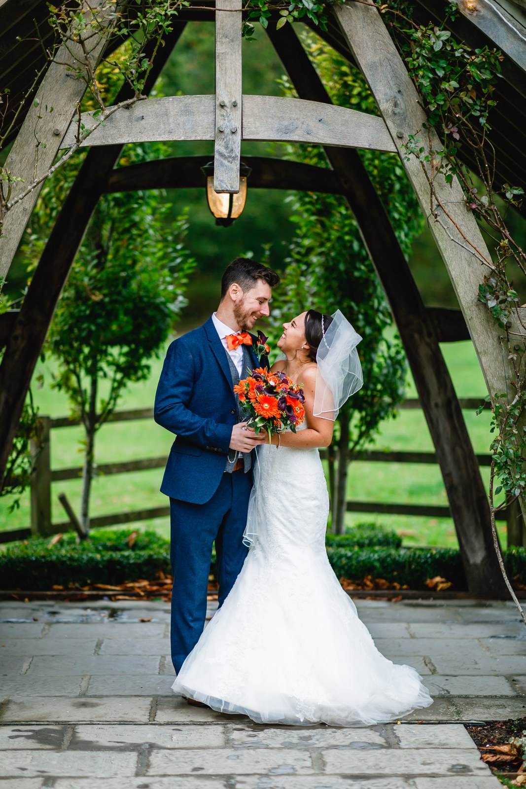 Bride and groom under the timbered garden arbour with the autumn bouquet