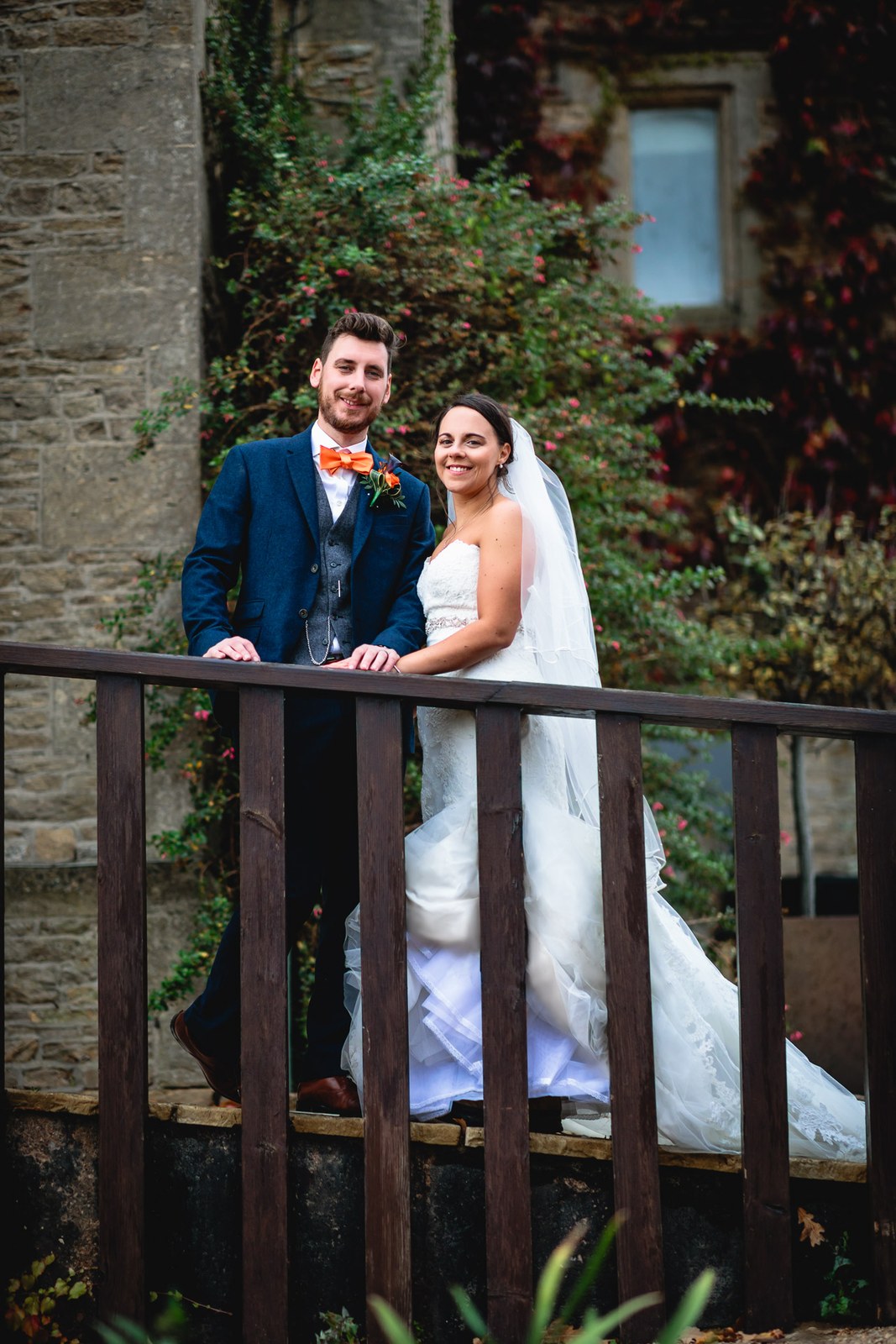 Bride and groom on the timber balcony framed by autumn creeper