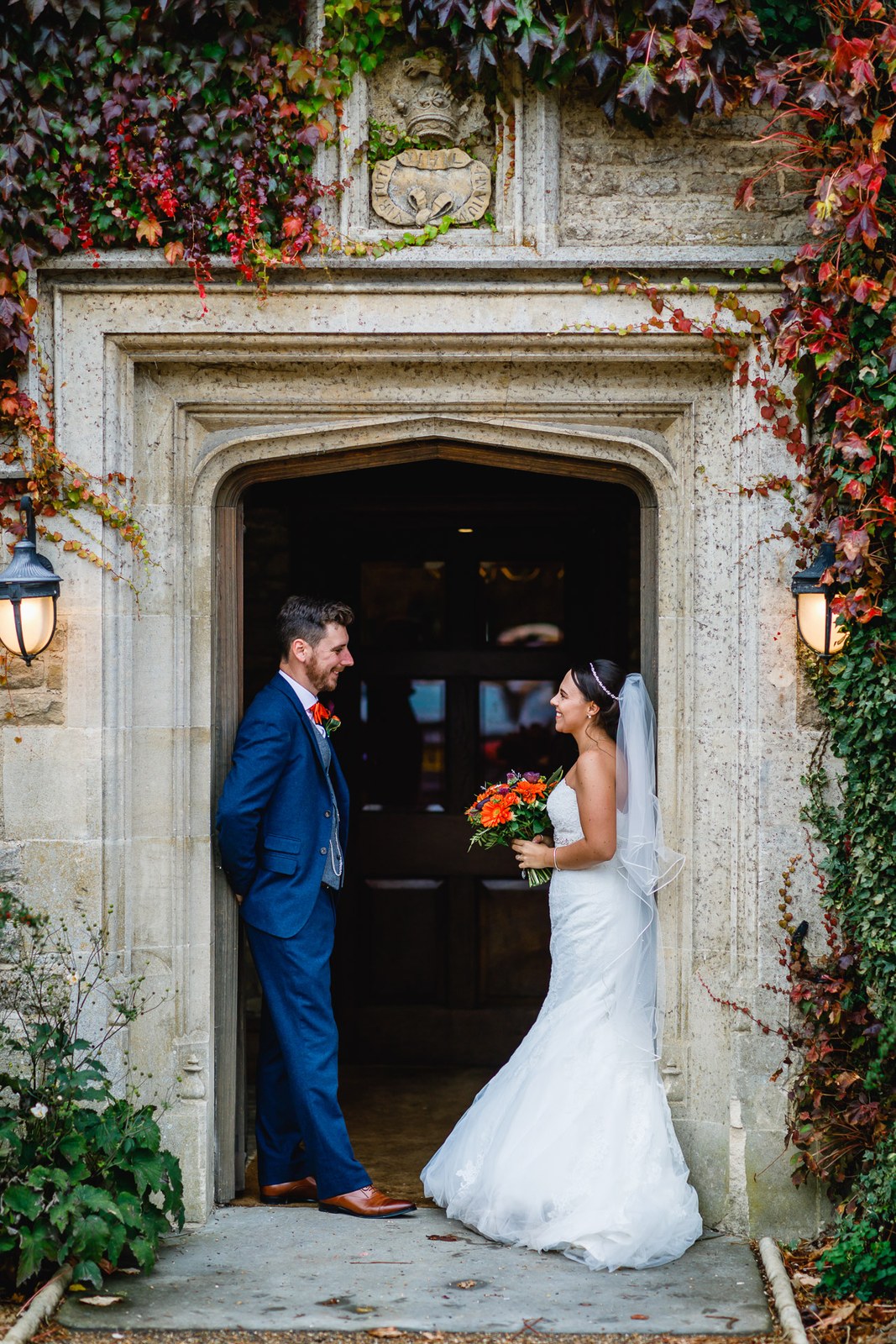 The couple in the arched Tudor doorway wreathed in autumn creeper at Hyde House