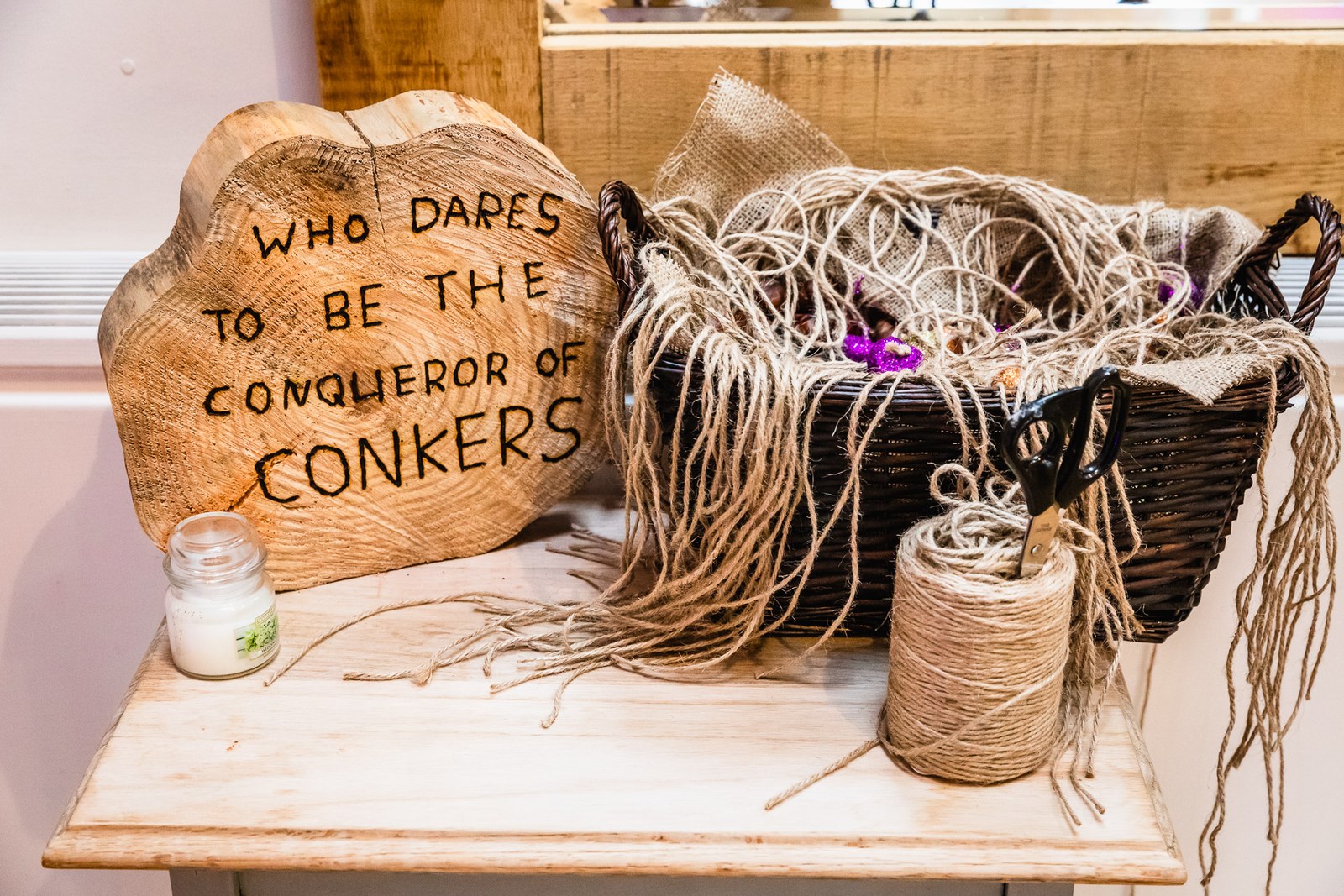 A rustic conkers game set out on a table with a hand-lettered wooden sign