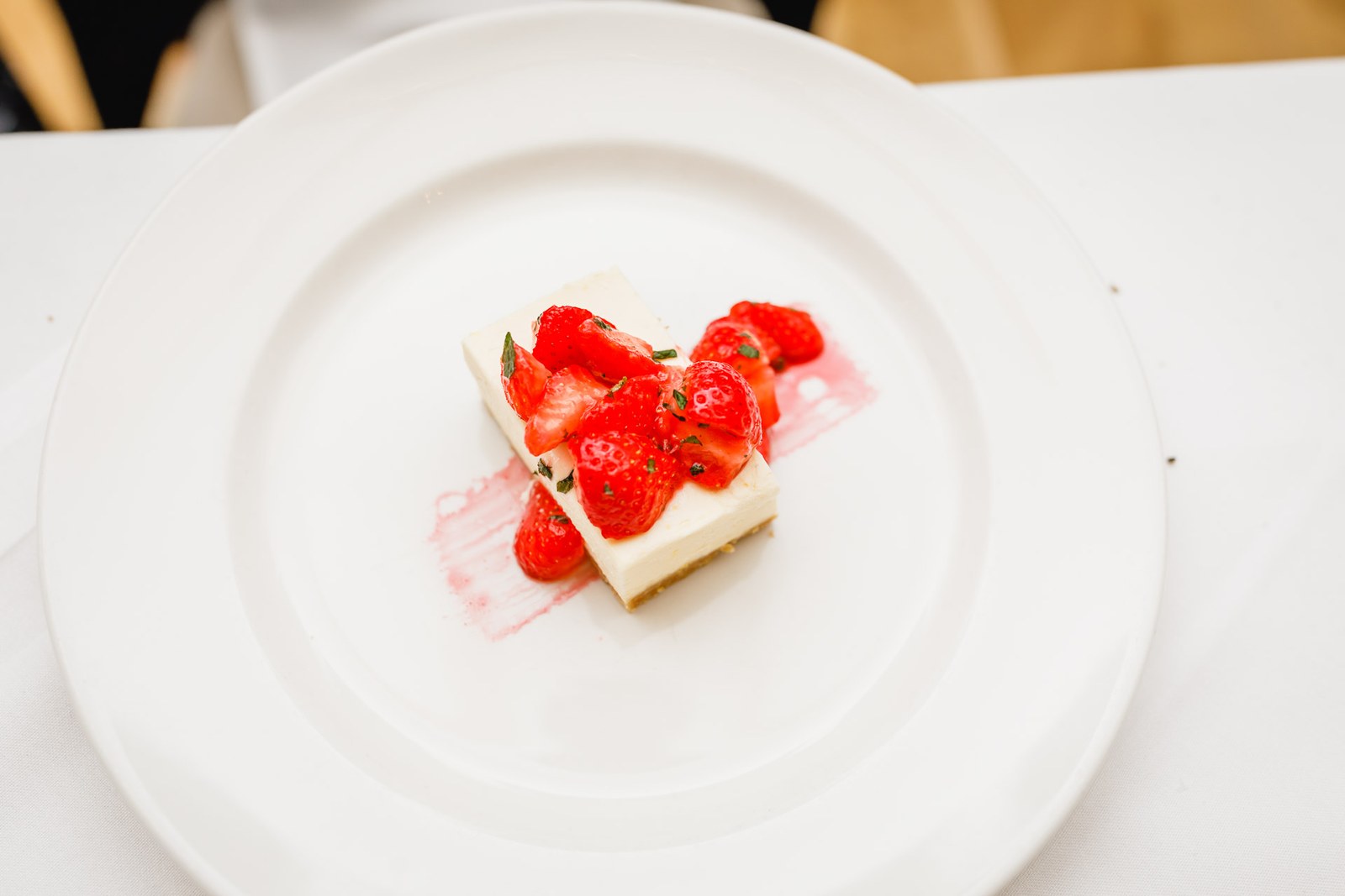 Overhead view of a strawberry-topped cheesecake dessert on a white plate