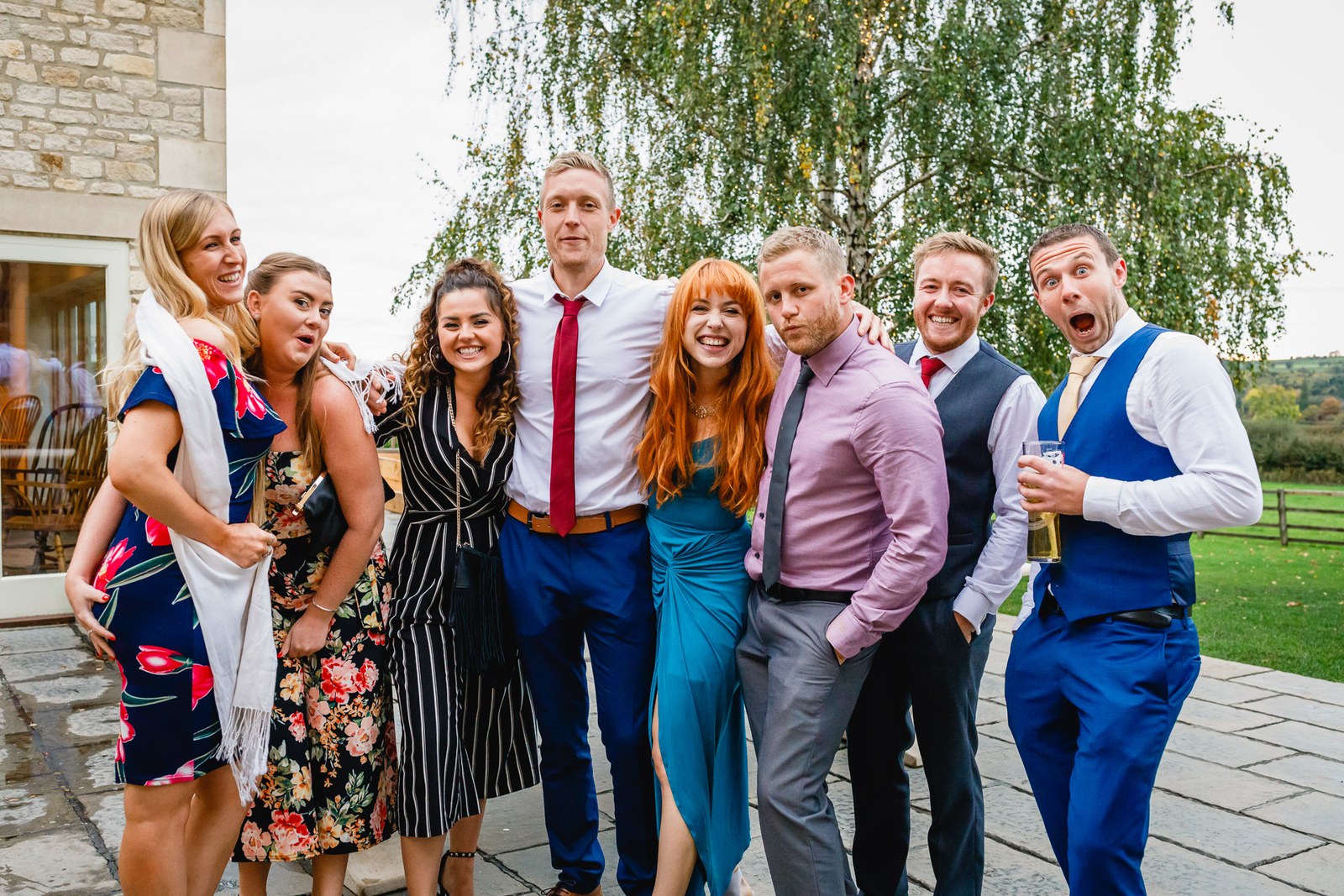 A cheerful group of guests posing together by a tree outside