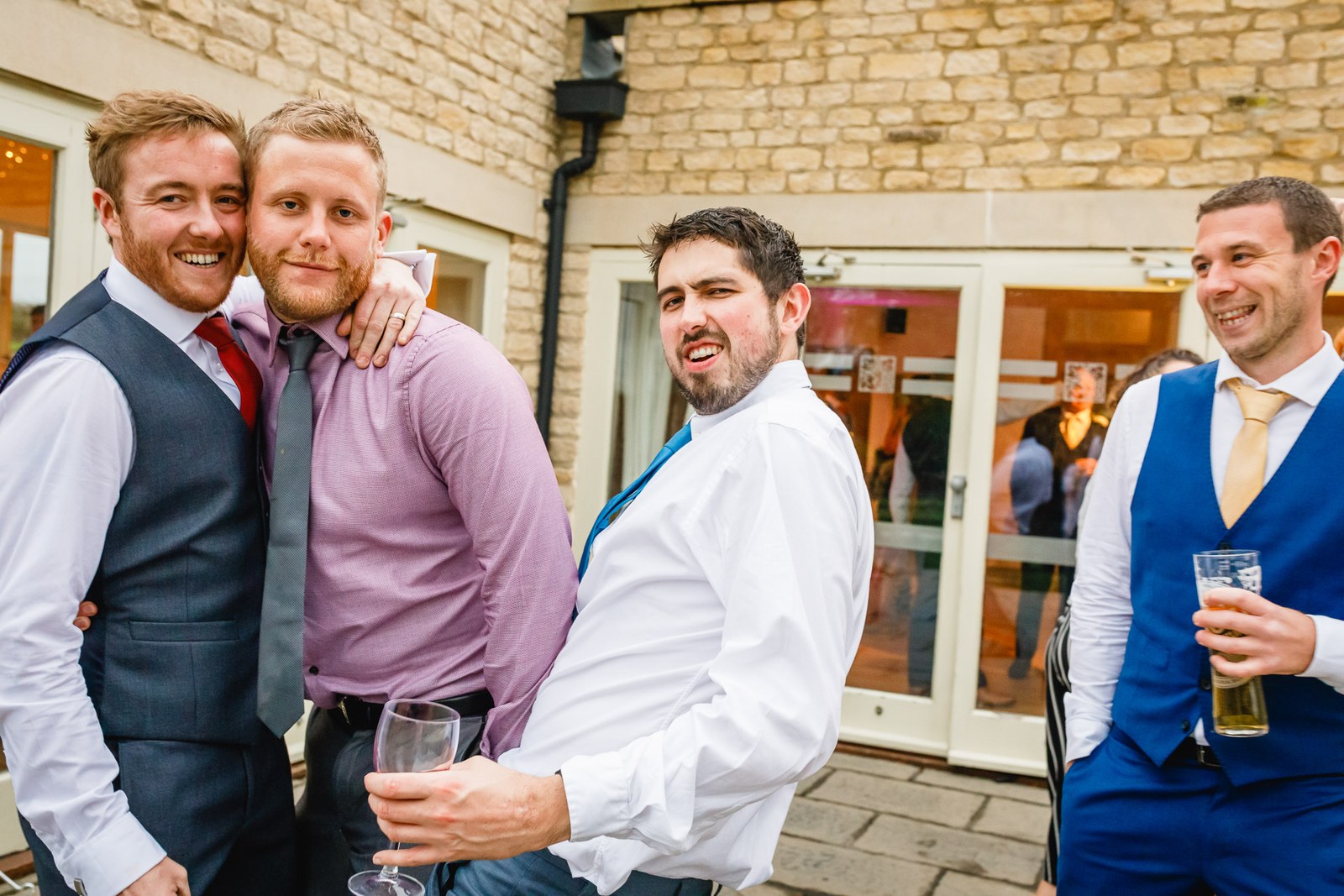 Male guests clowning around for a group photo at the reception