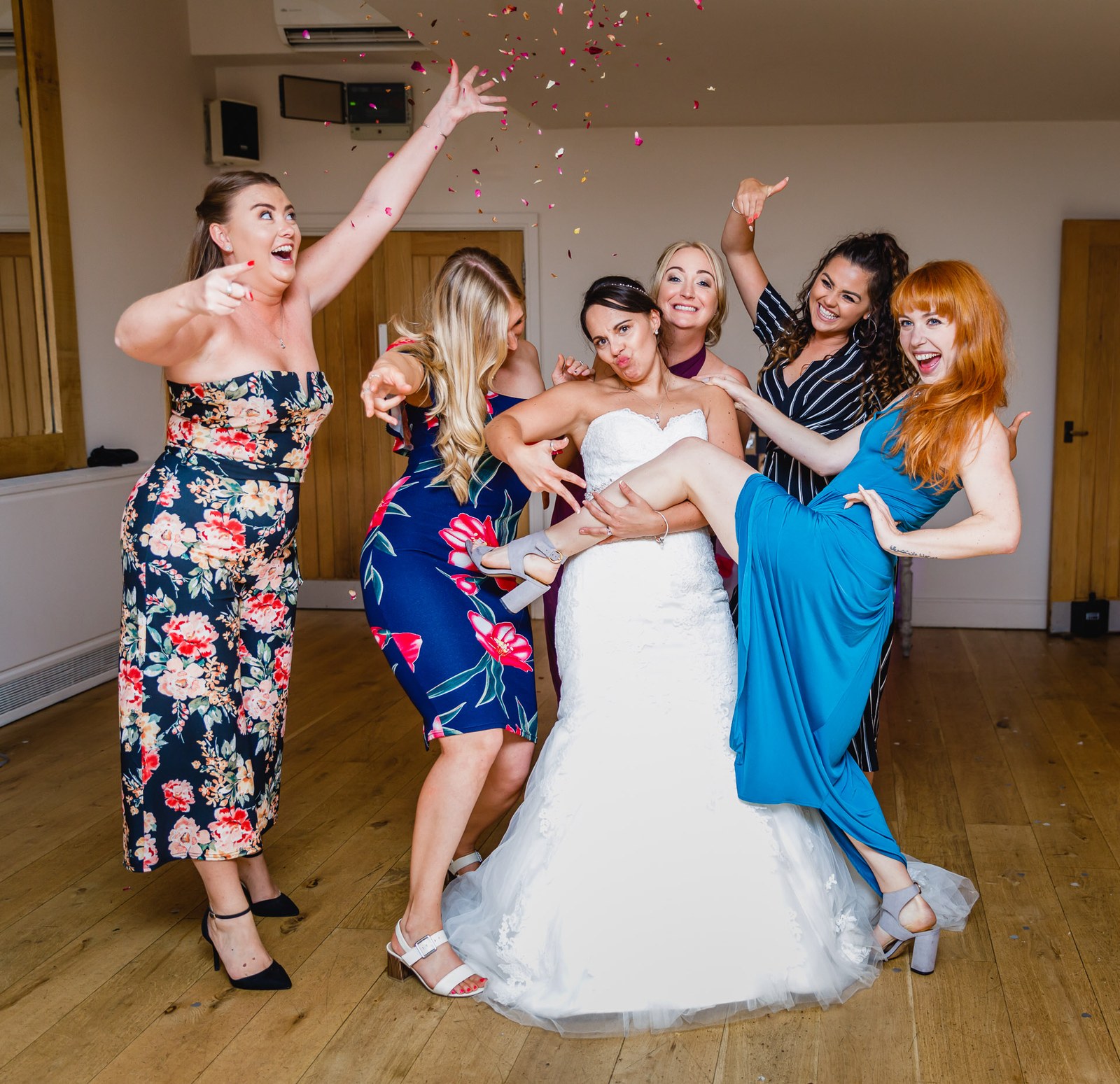 Guests posing around the laughing bride as confetti flies