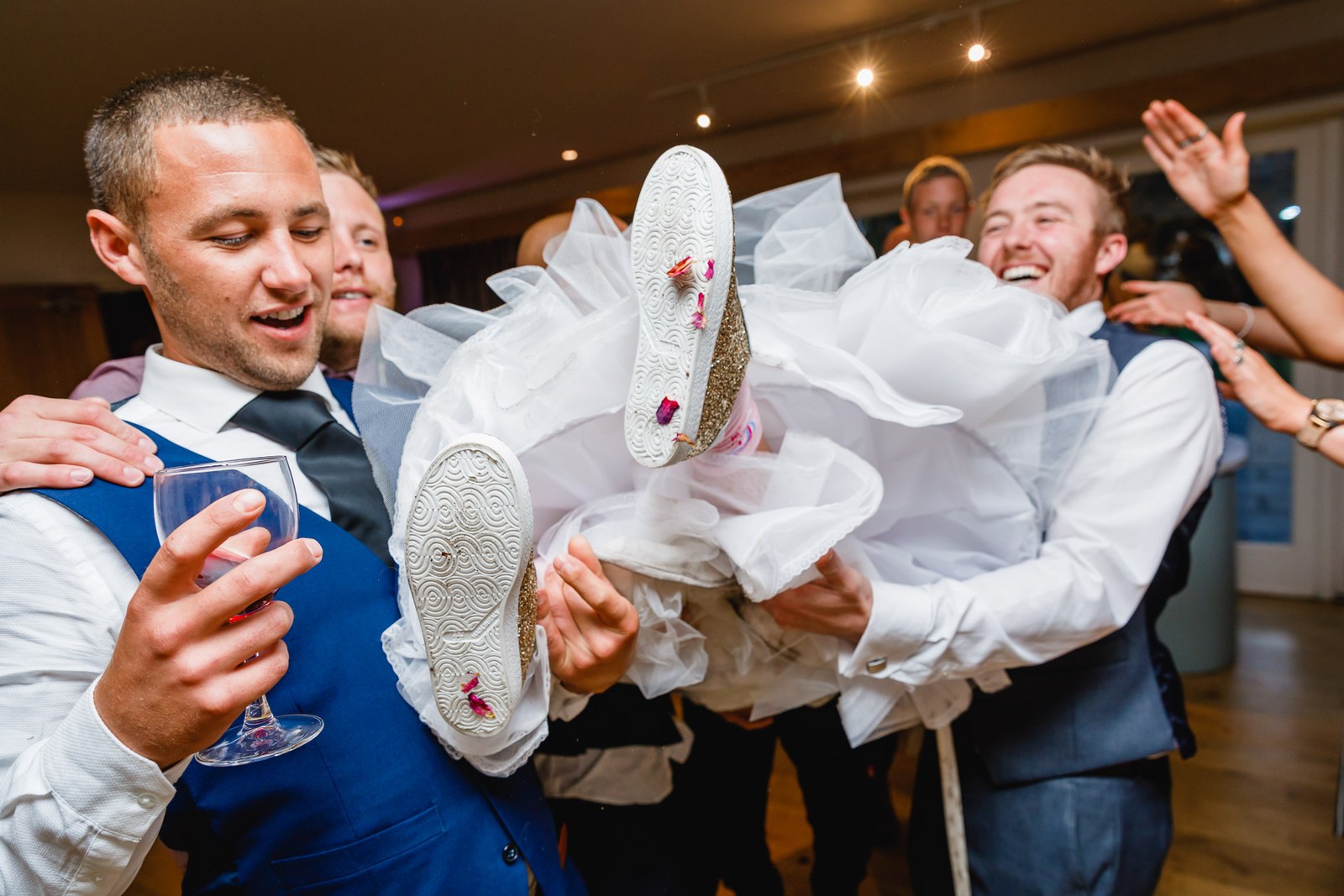Guests holding the bride up in a burst of party high jinks