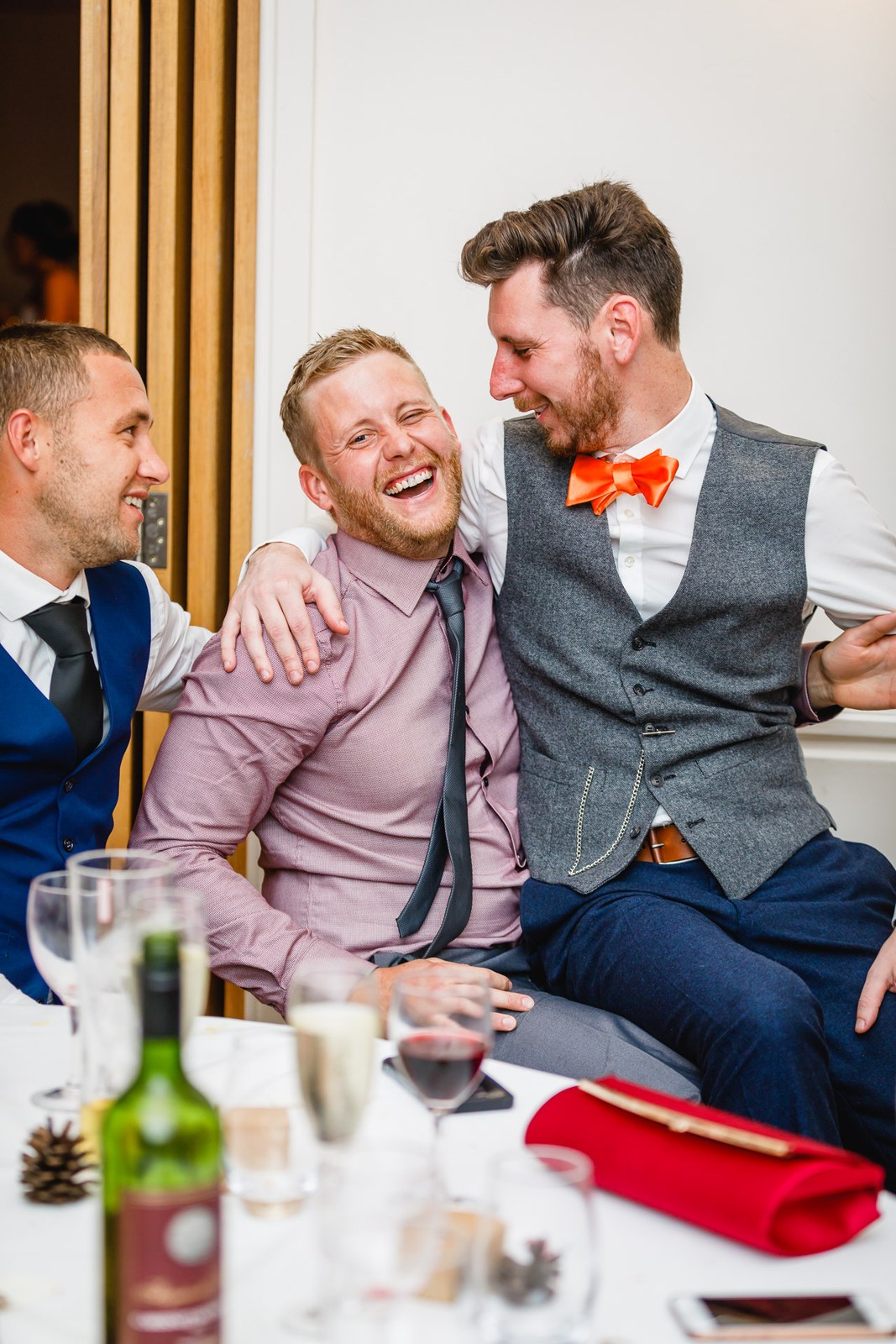 The groom laughing arm in arm with two guests during the celebrations