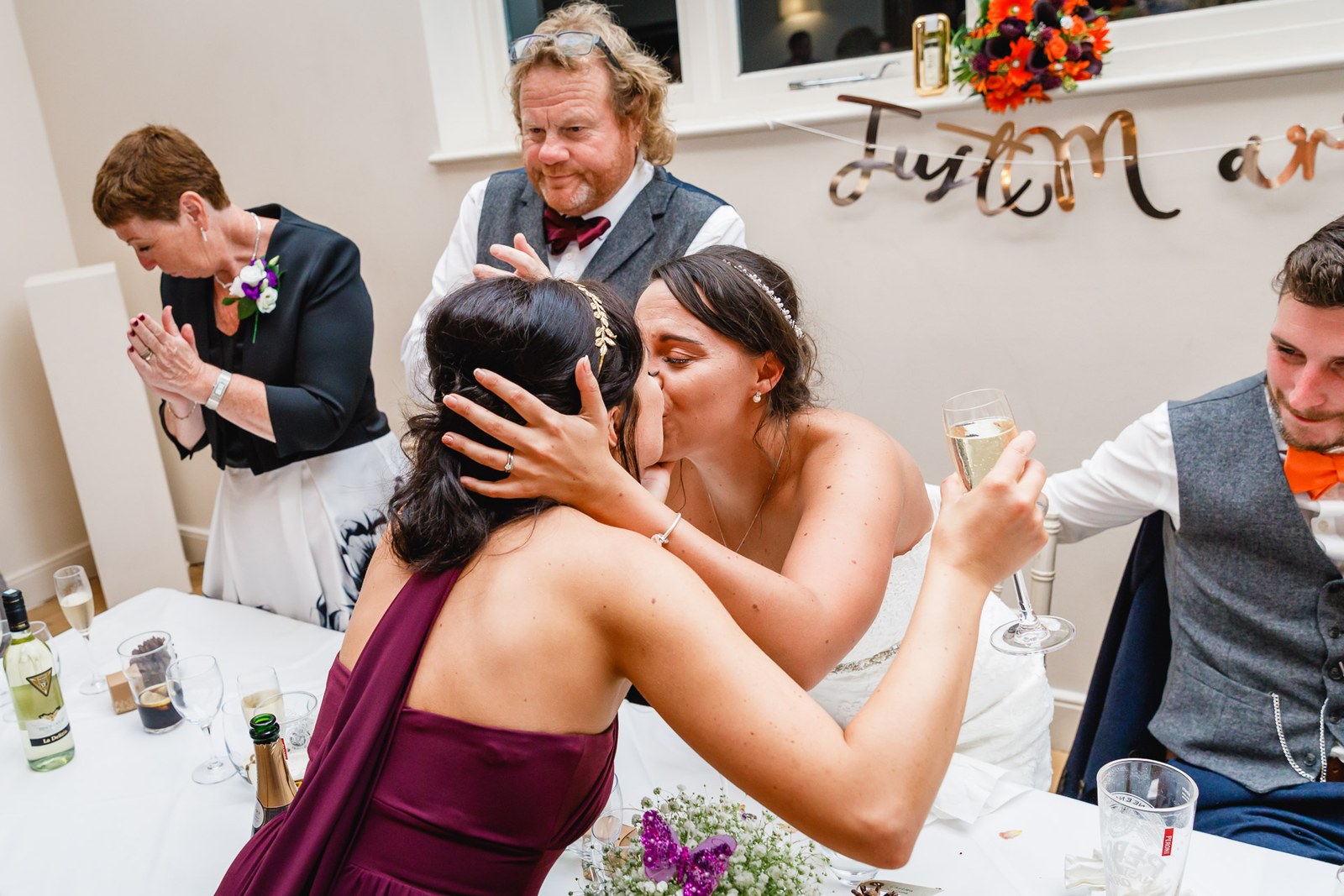 The bride hugging a bridesmaid at the top table during the speeches