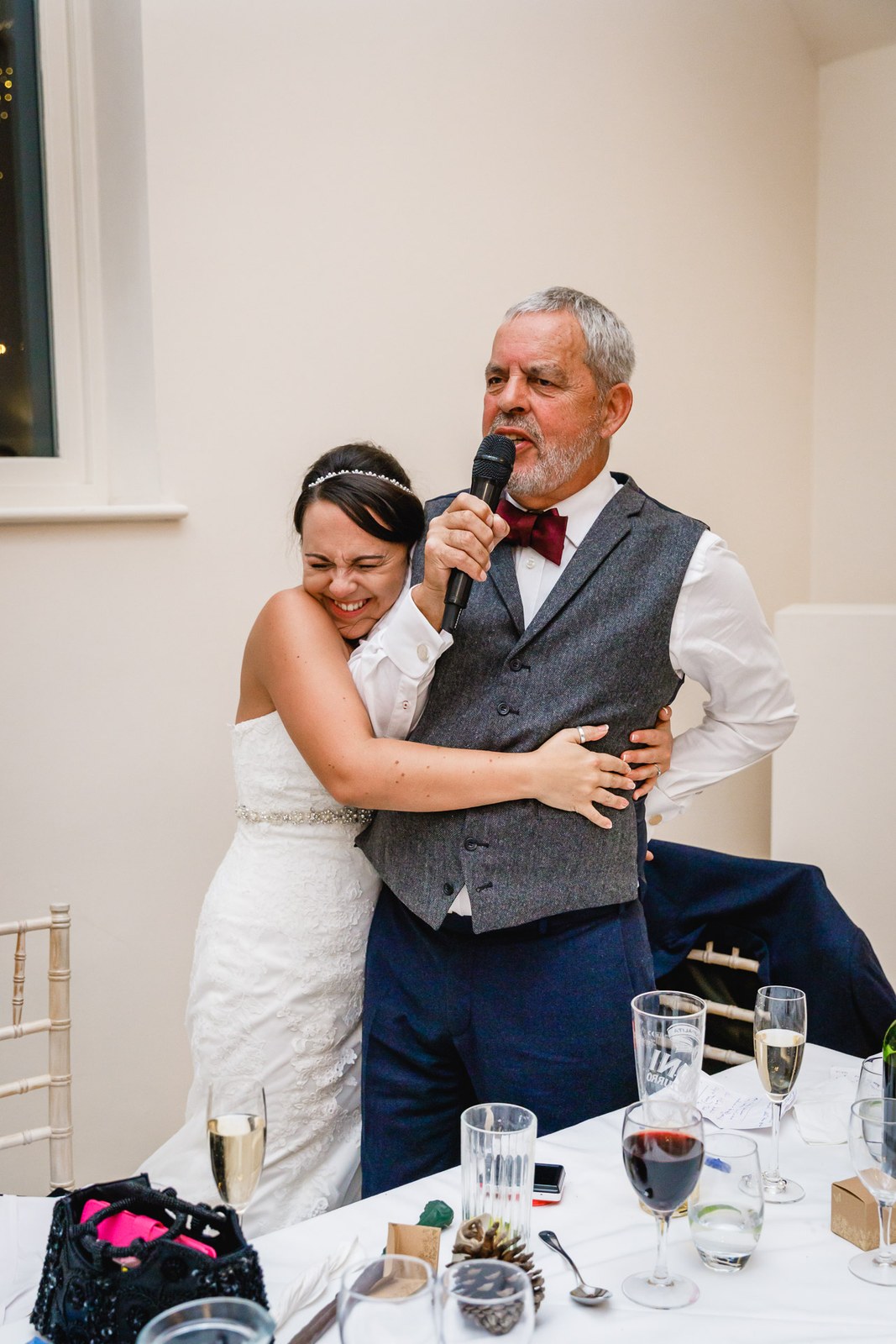 The bride hugging her father as he gives a speech at the top table