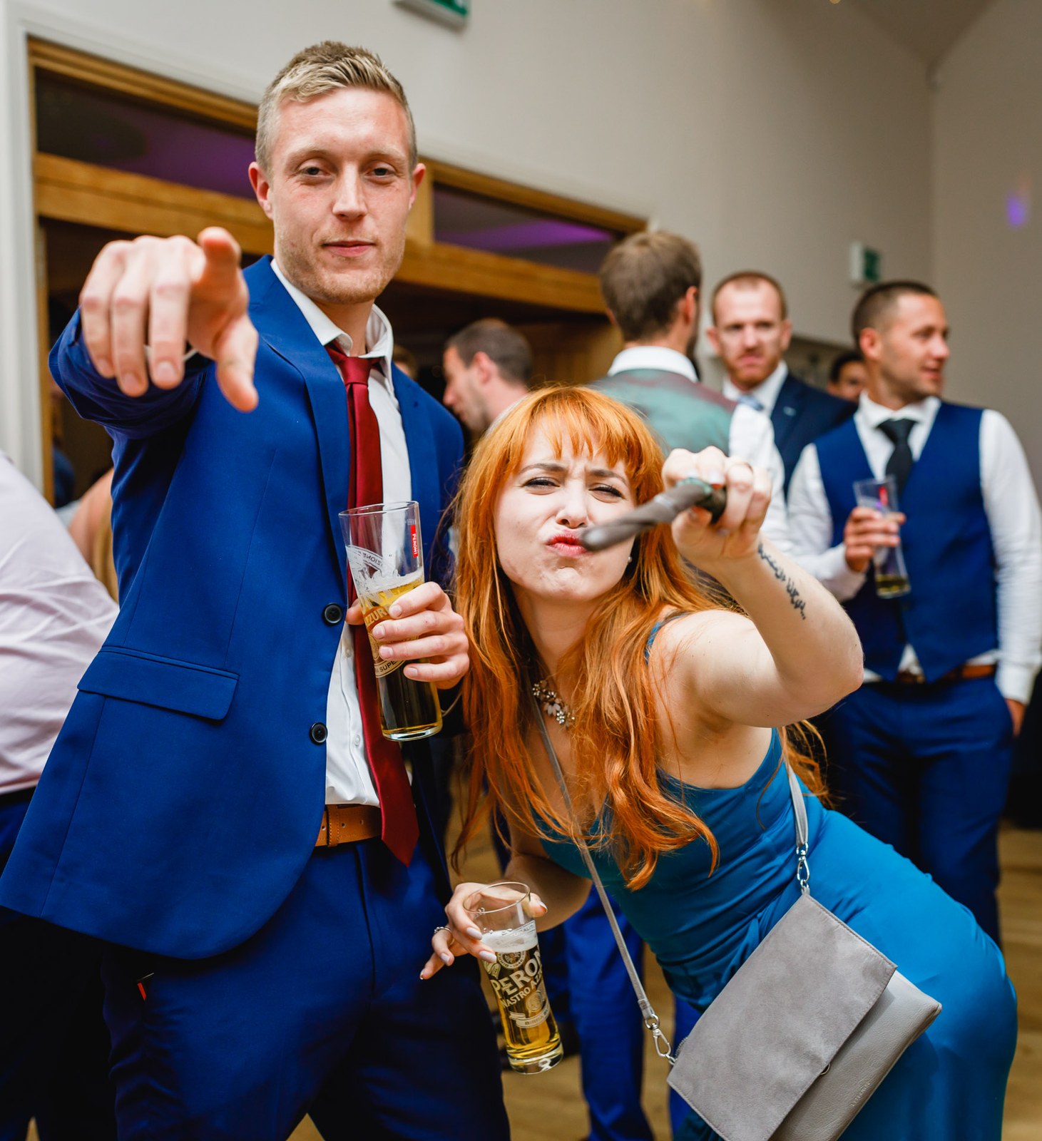 A guest pointing to camera as another blows a party horn on the dance floor