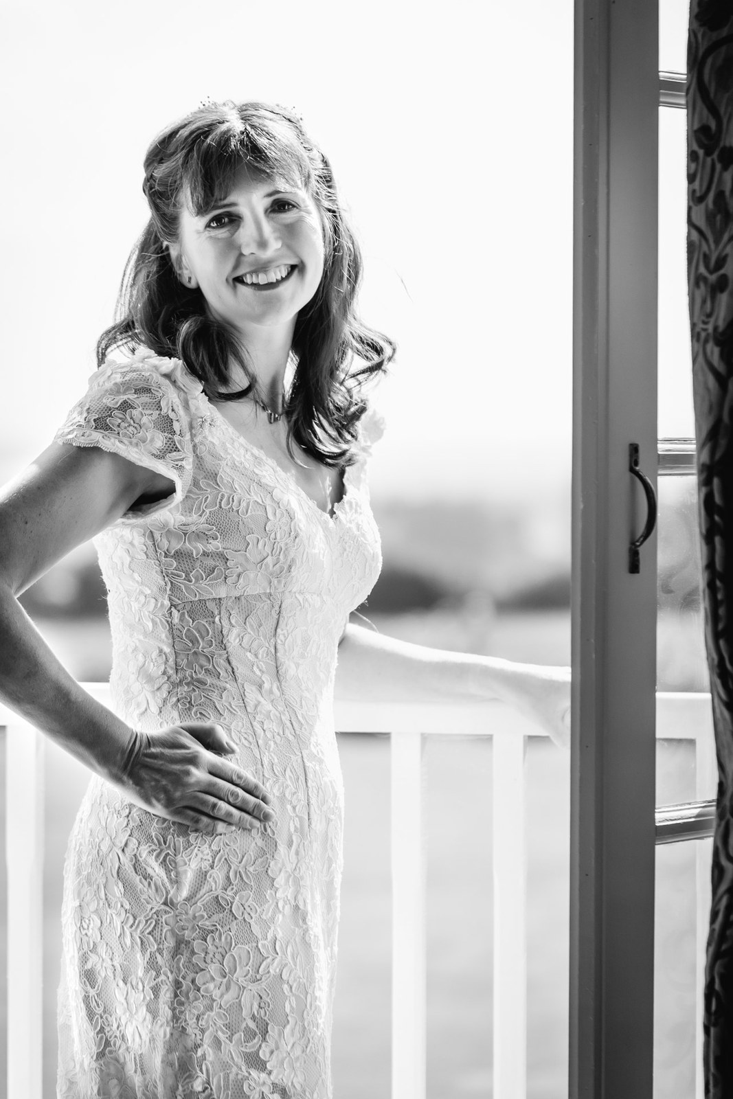 Black and white portrait of the smiling bride in a sunlit doorway