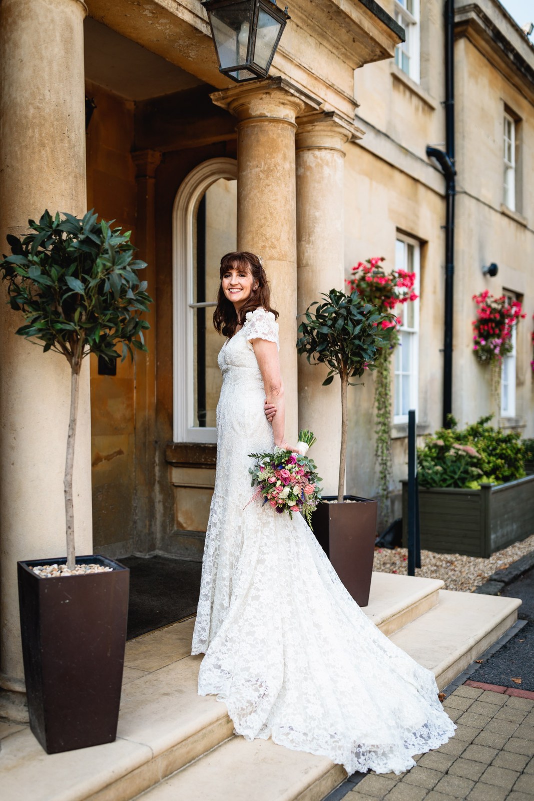 Bride on the steps of Leigh Park Country House Hotel between clipped bay trees