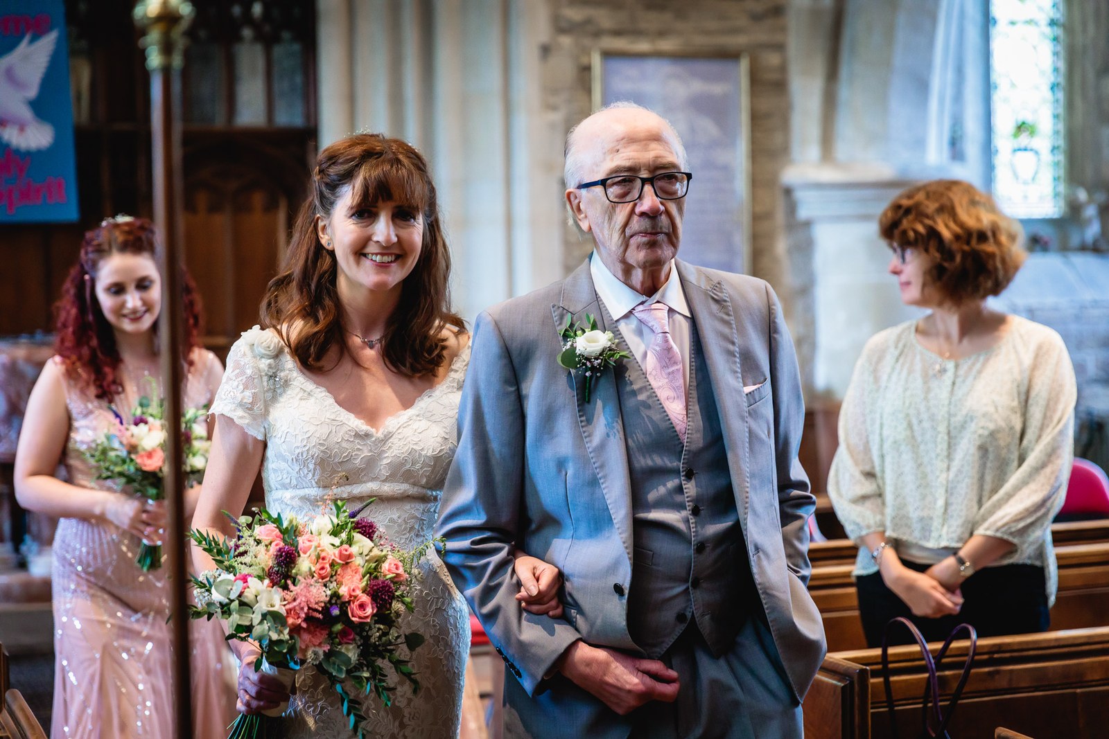 Bride on her father's arm at the front of the church, holding her bouquet