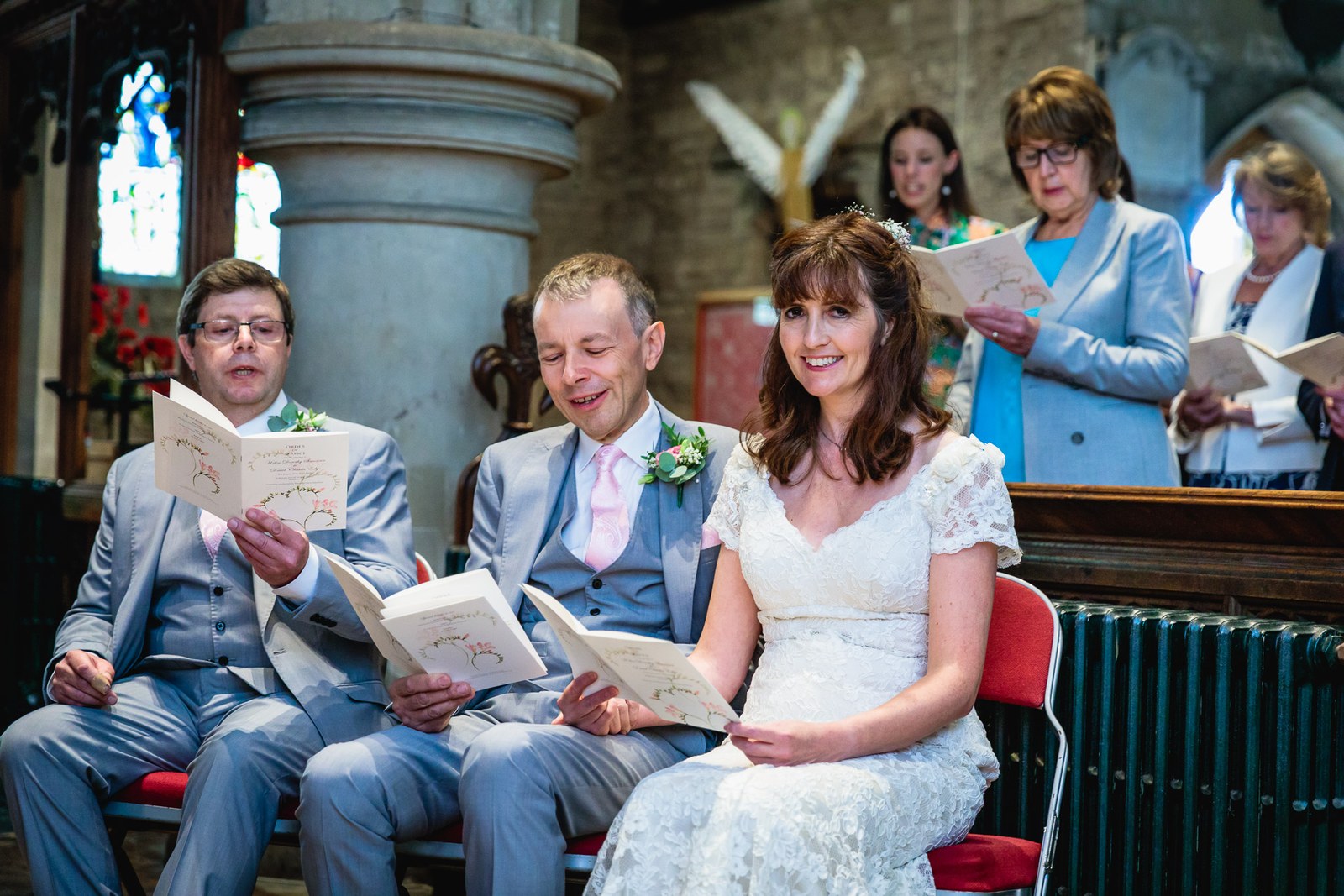 Bride and groom seated together reading their orders of service during the ceremony