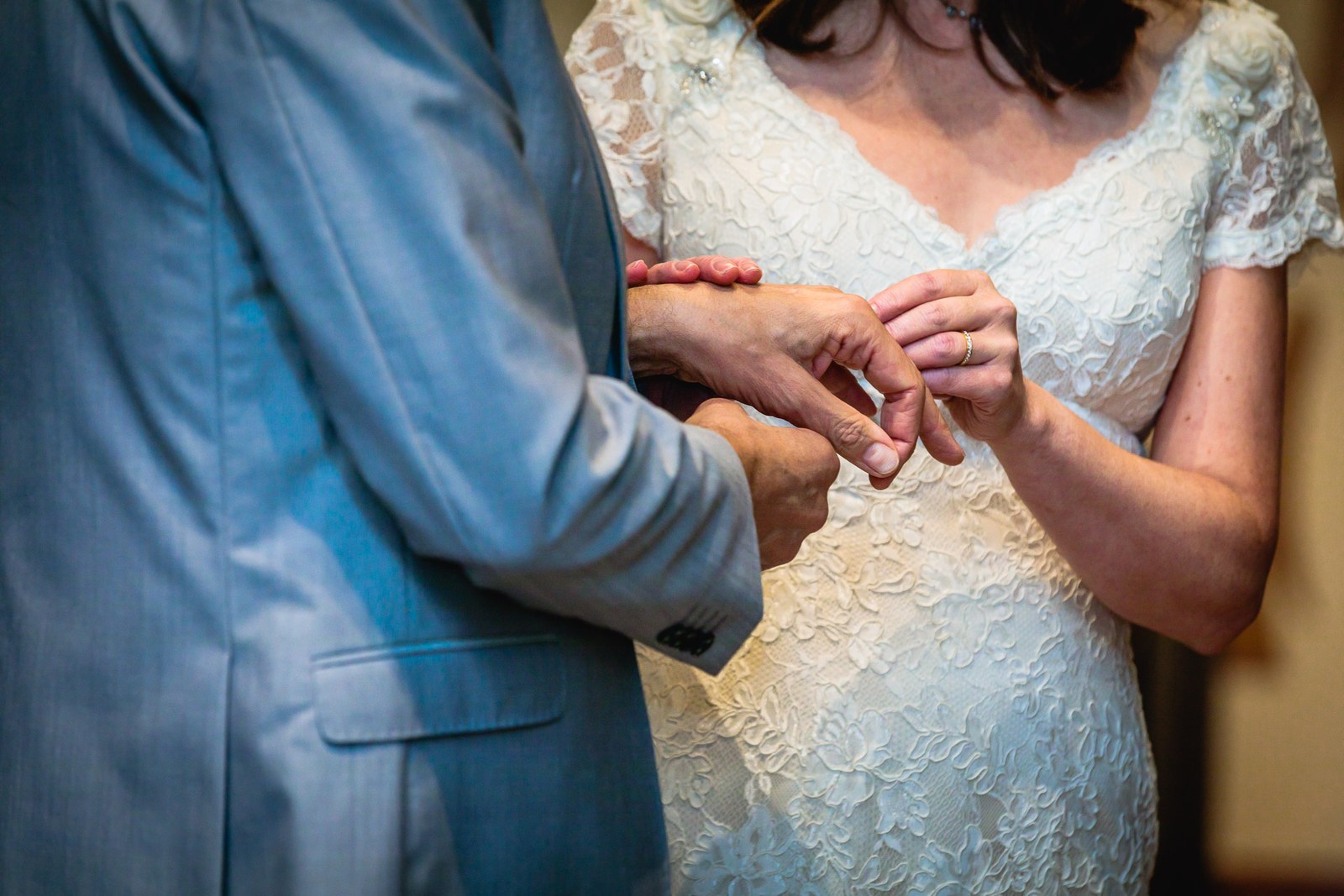 Close-up of the bride sliding the wedding ring onto the groom's finger