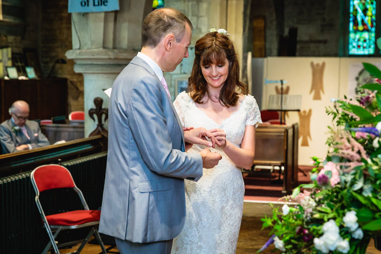 The couple exchanging rings at the altar with flowers in the foreground