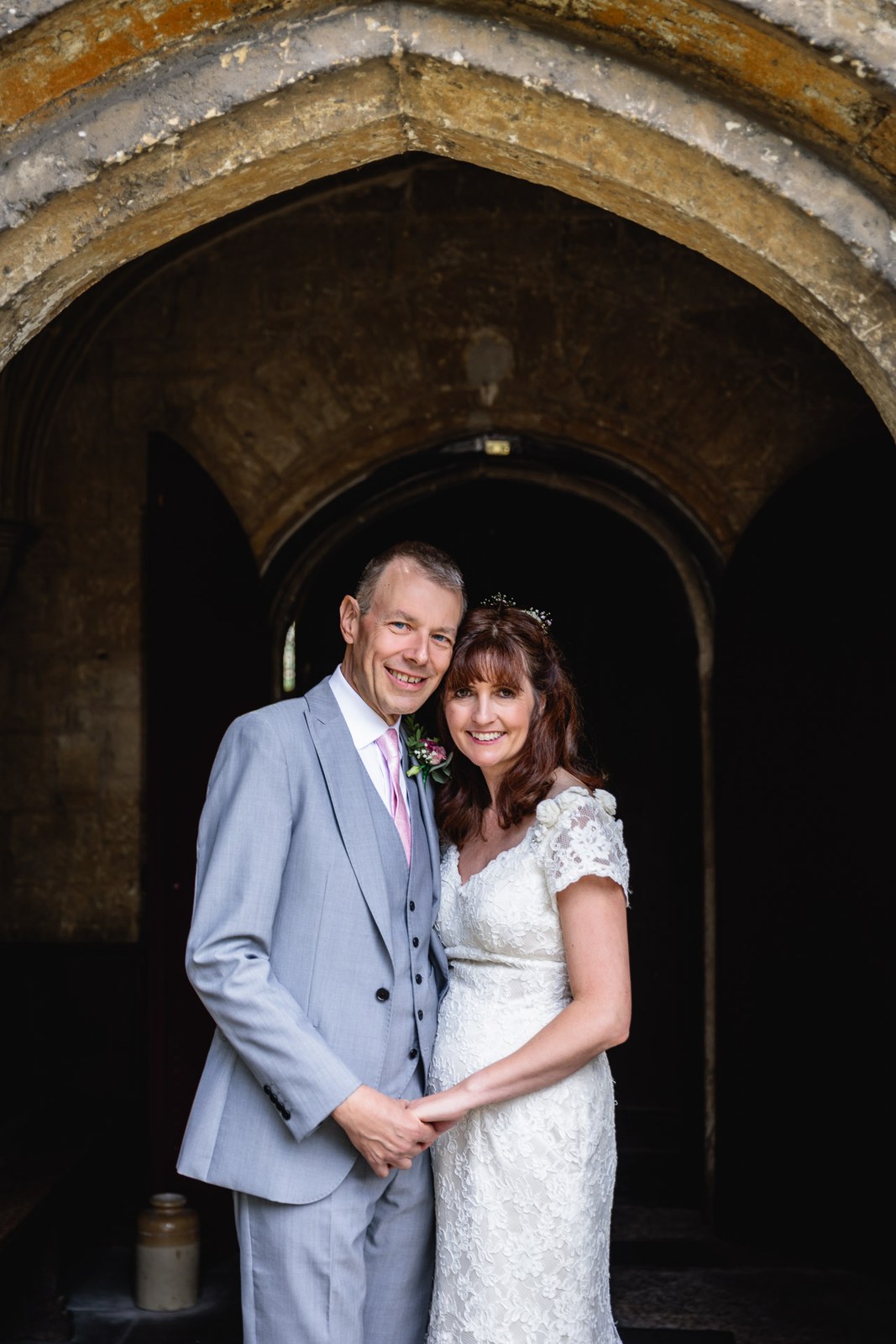 Bride and groom embracing under the pointed stone porch of the church