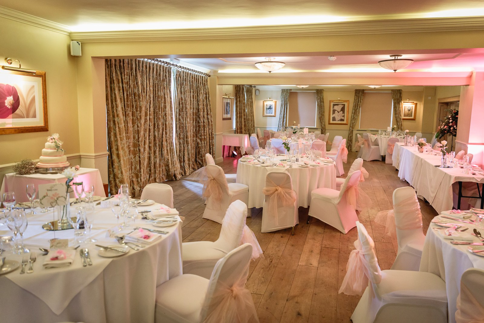The hotel reception room set for the wedding breakfast with round tables and chair sashes